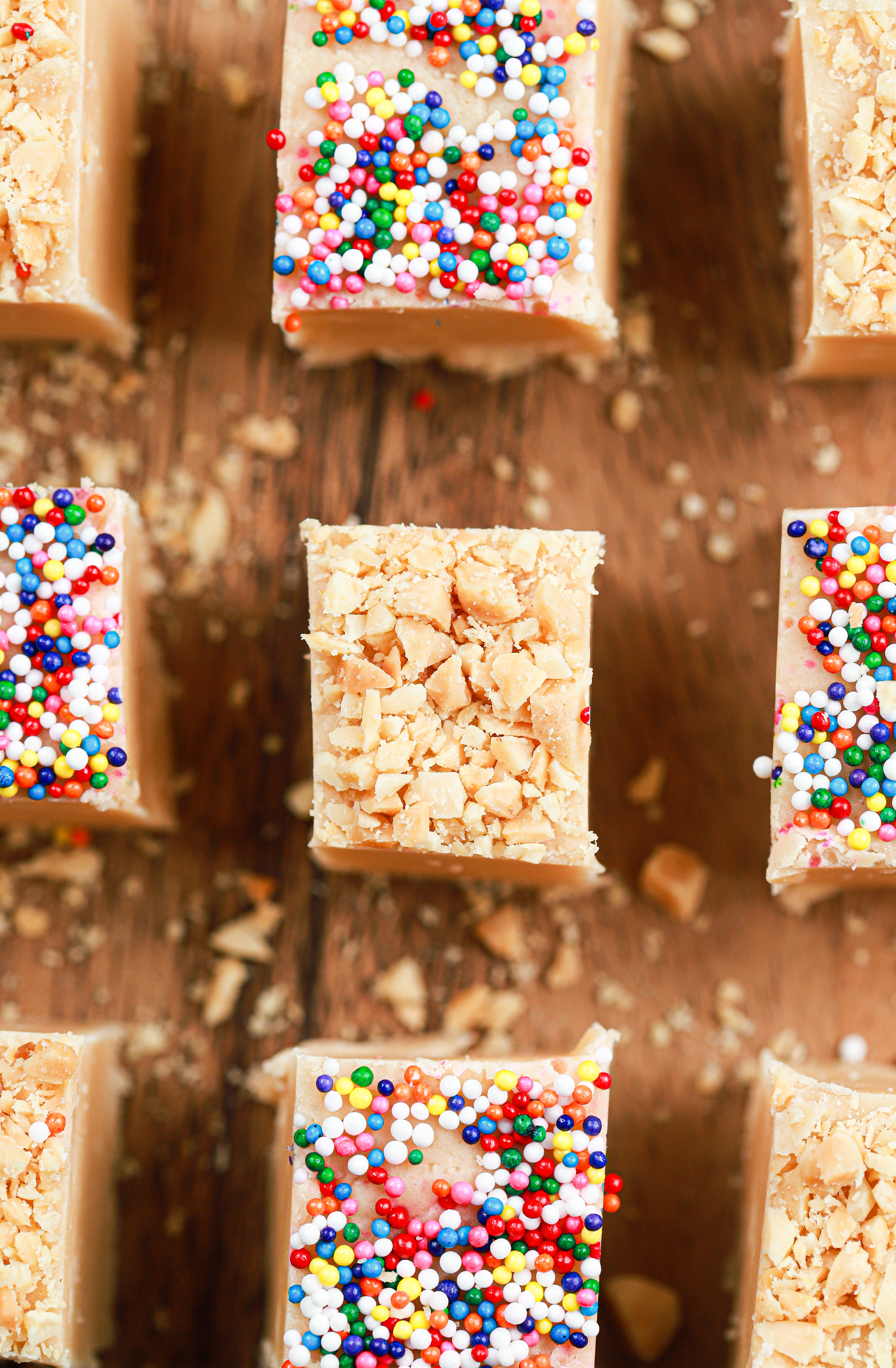Up close overhead view of a piece of easy peanut butter fudge topped with crushed peanuts on a wooden cutting board.