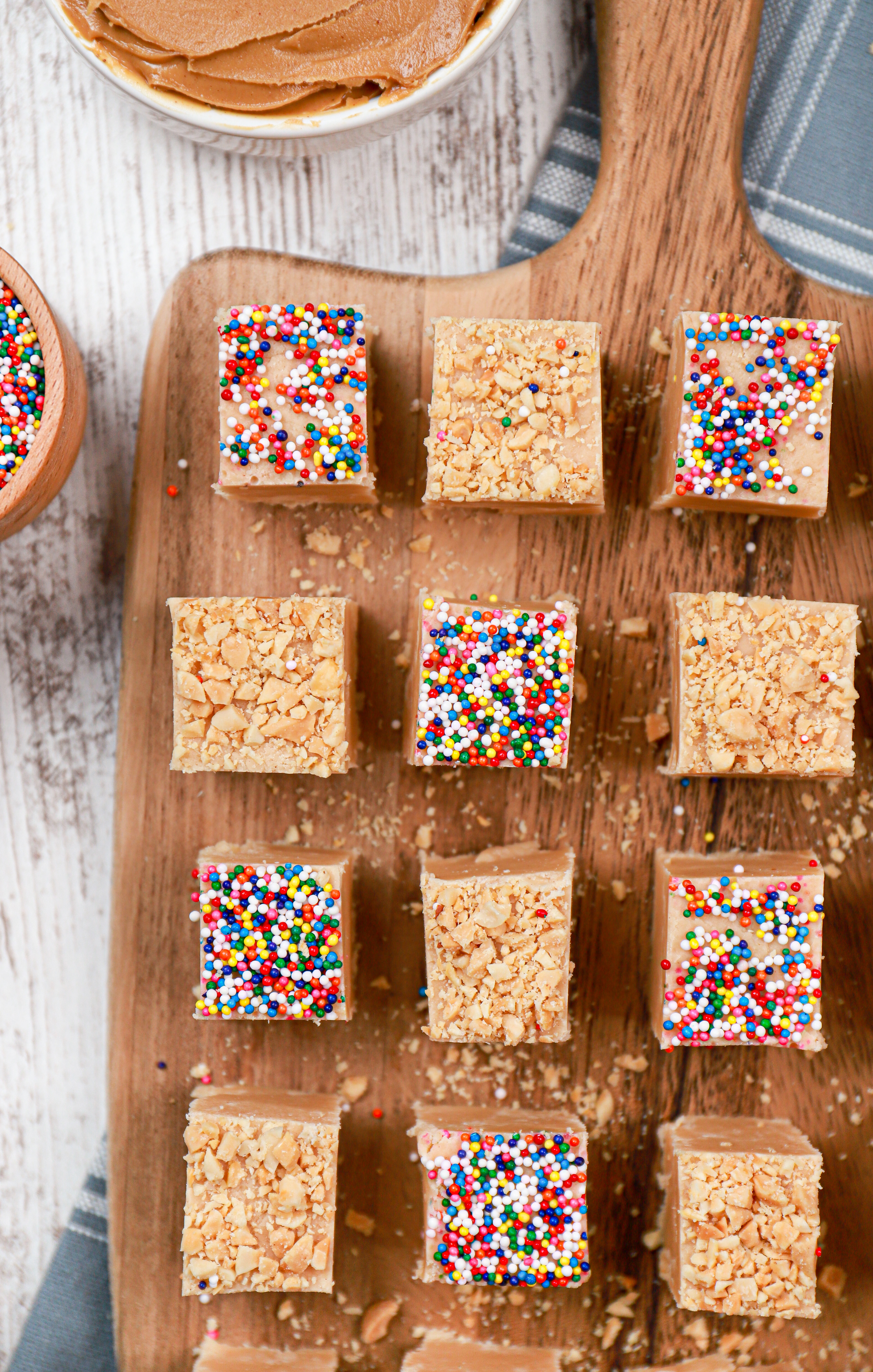 Overhead view of a batch of creamy peanut butter fudge cut into pieces on a wooden cutting board.
