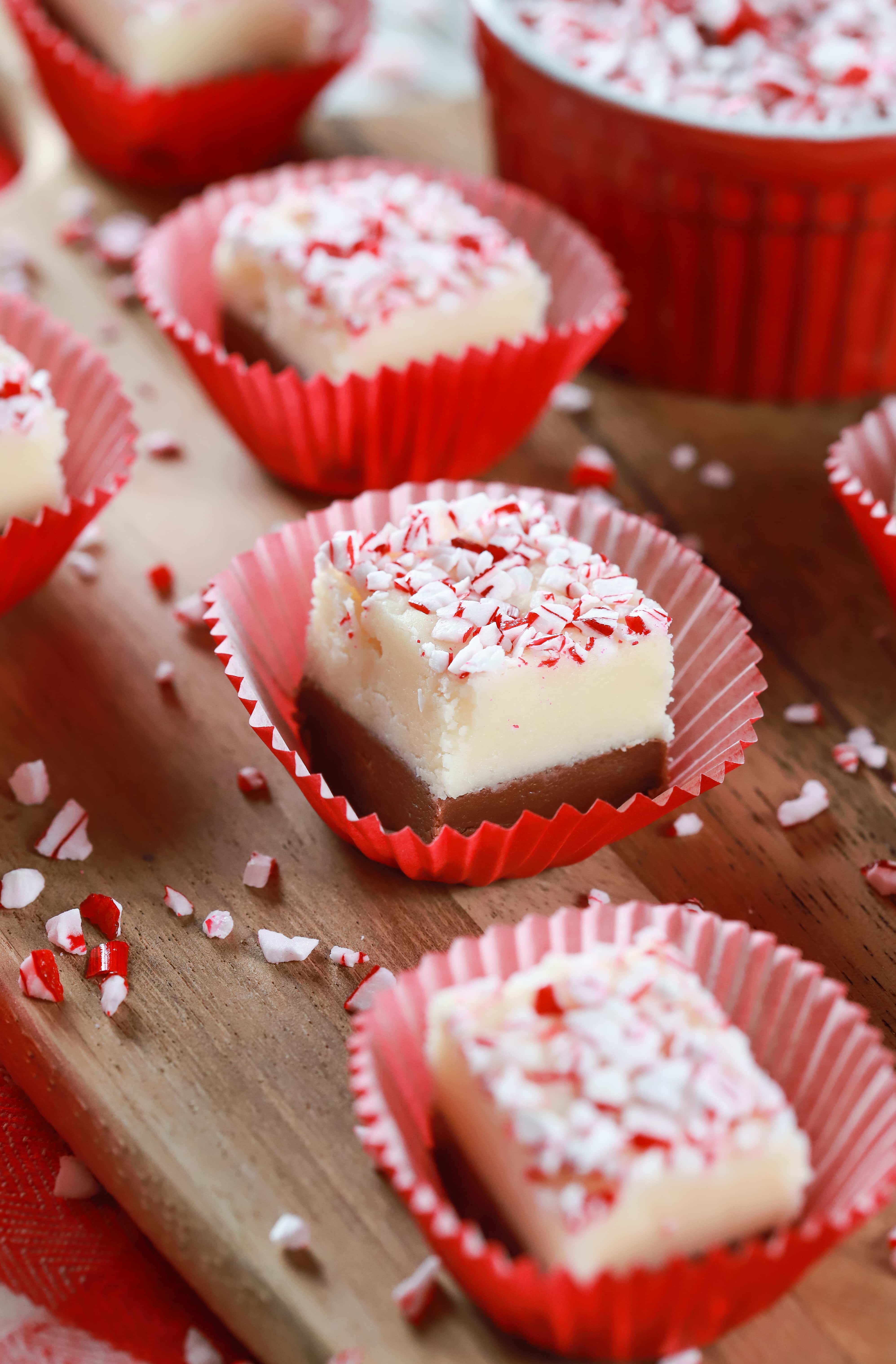 Up close image of a piece of chocolate peppermint layered fudge in a red cupcake liner on a wooden cutting board. Recipe from A Kitchen Addiction