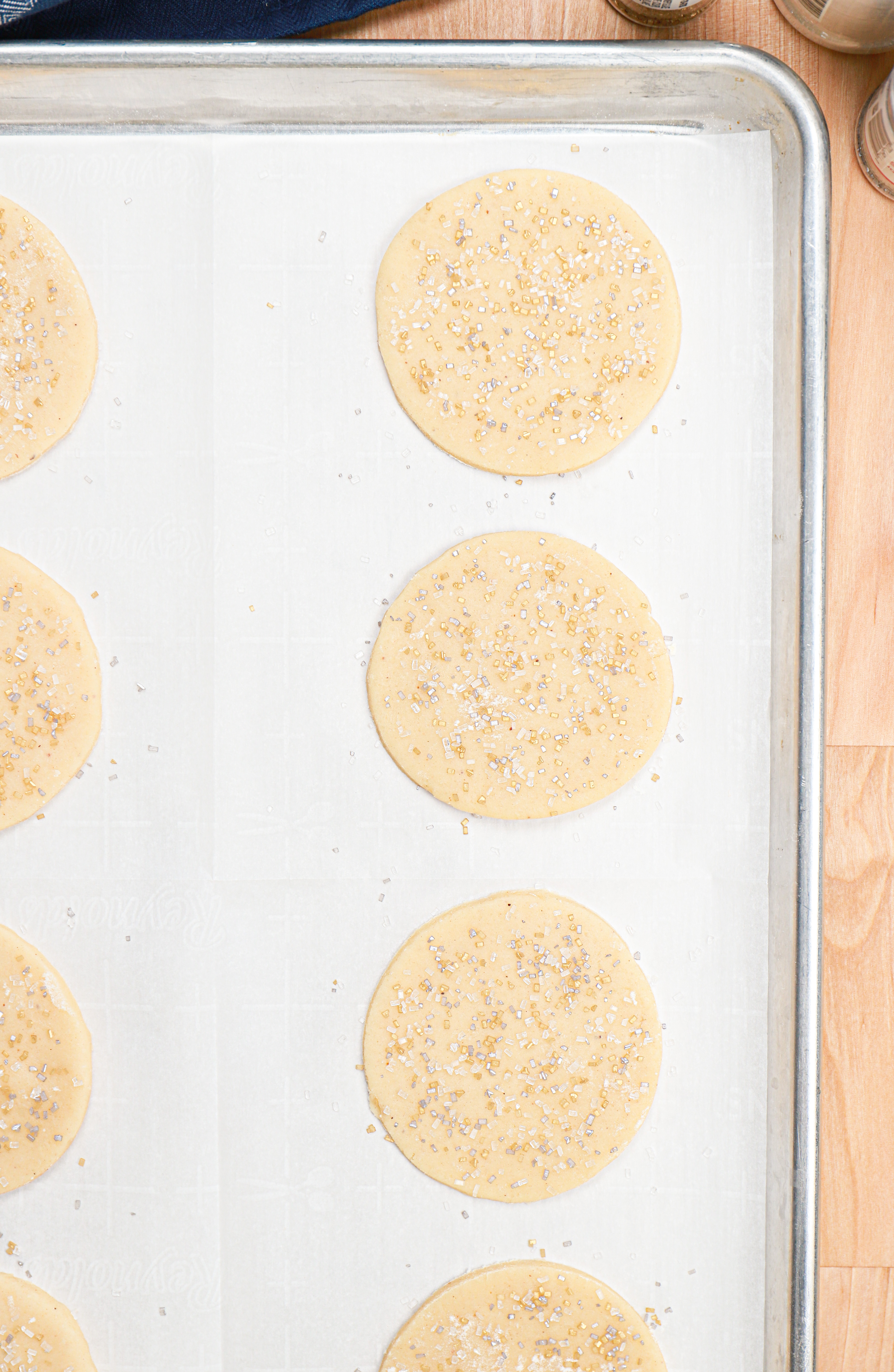 Sour cream cookie dough cut outs on a parchment paper lined cookie sheet before baking.