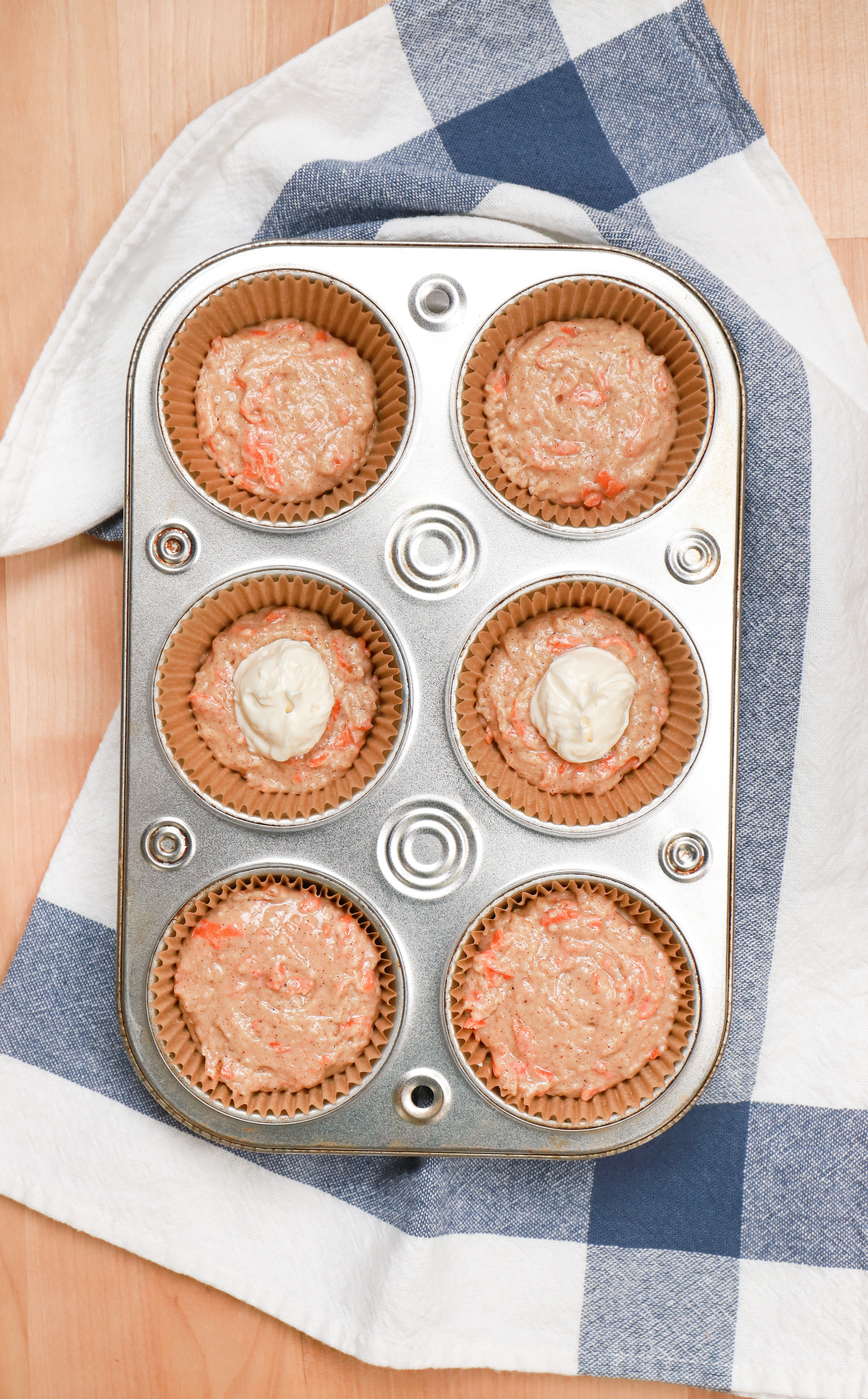 Overhead view of cream cheese filled carrot cake muffin batter in muffin tin before baking.
