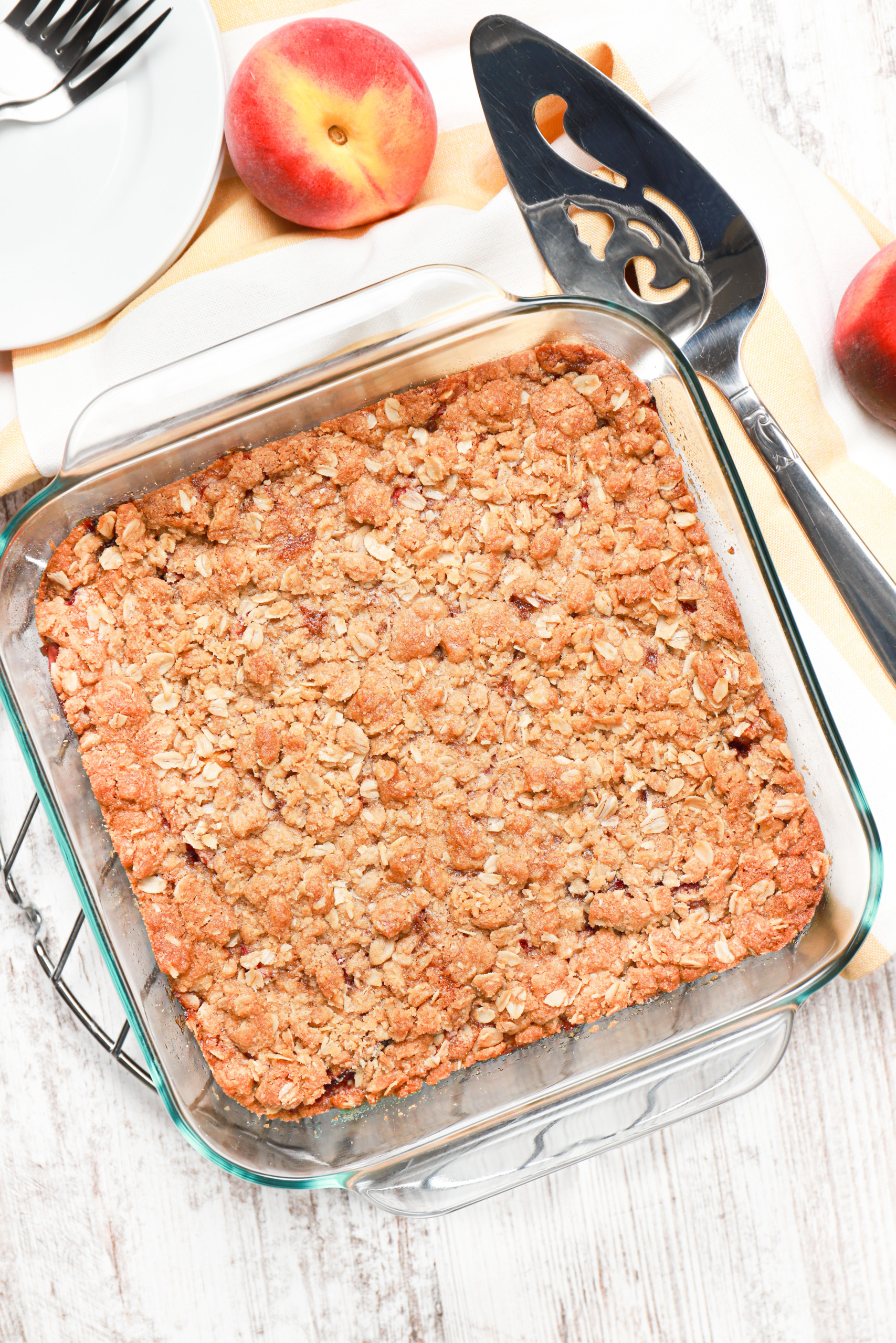 Overhead view of a pan of strawberry peach streusel bars fresh from the oven with a drizzle.