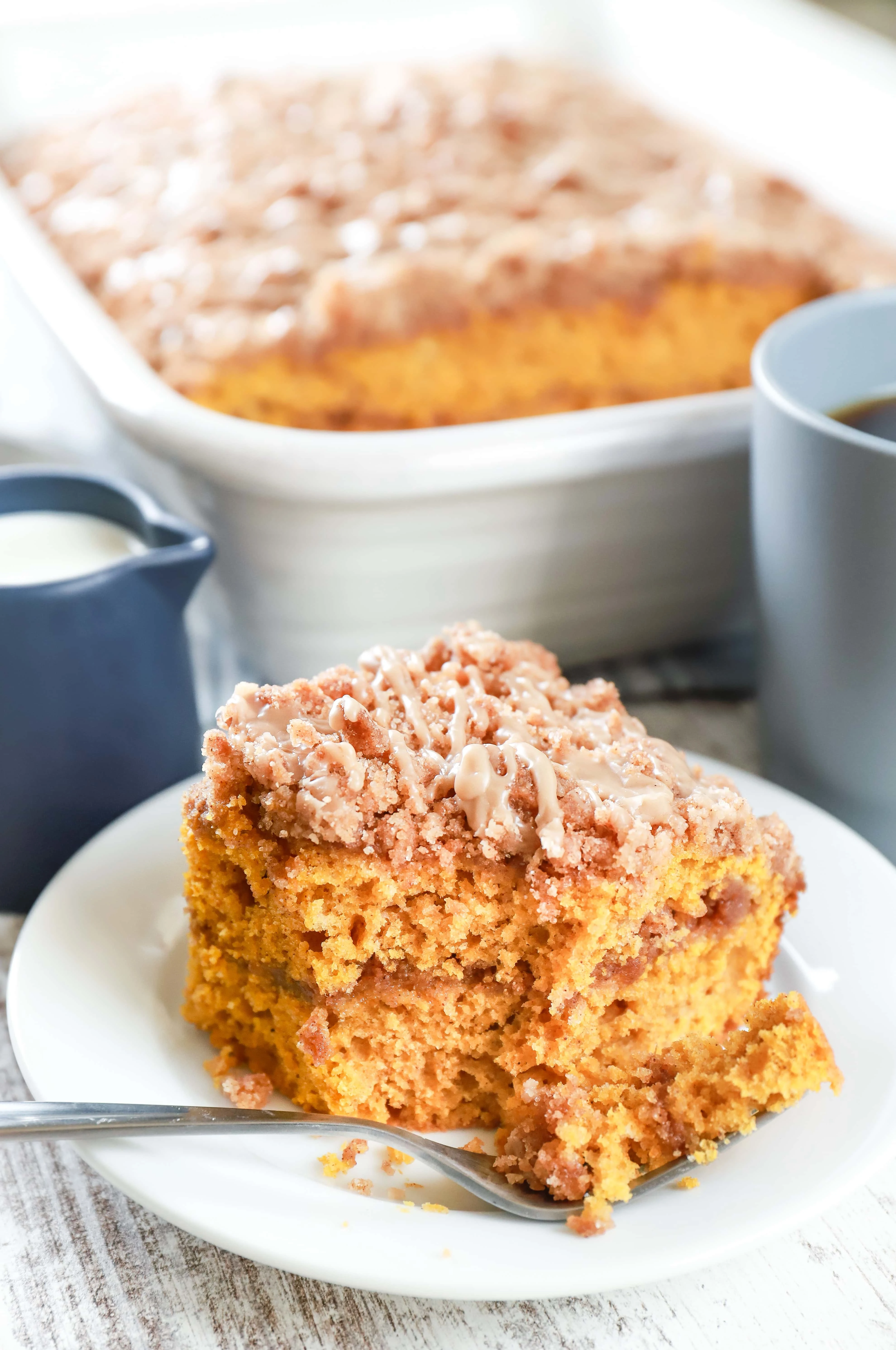 Up close image of a piece of maple cinnamon pumpkin coffee cake on a white plate. Recipe from A Kitchen Addiction