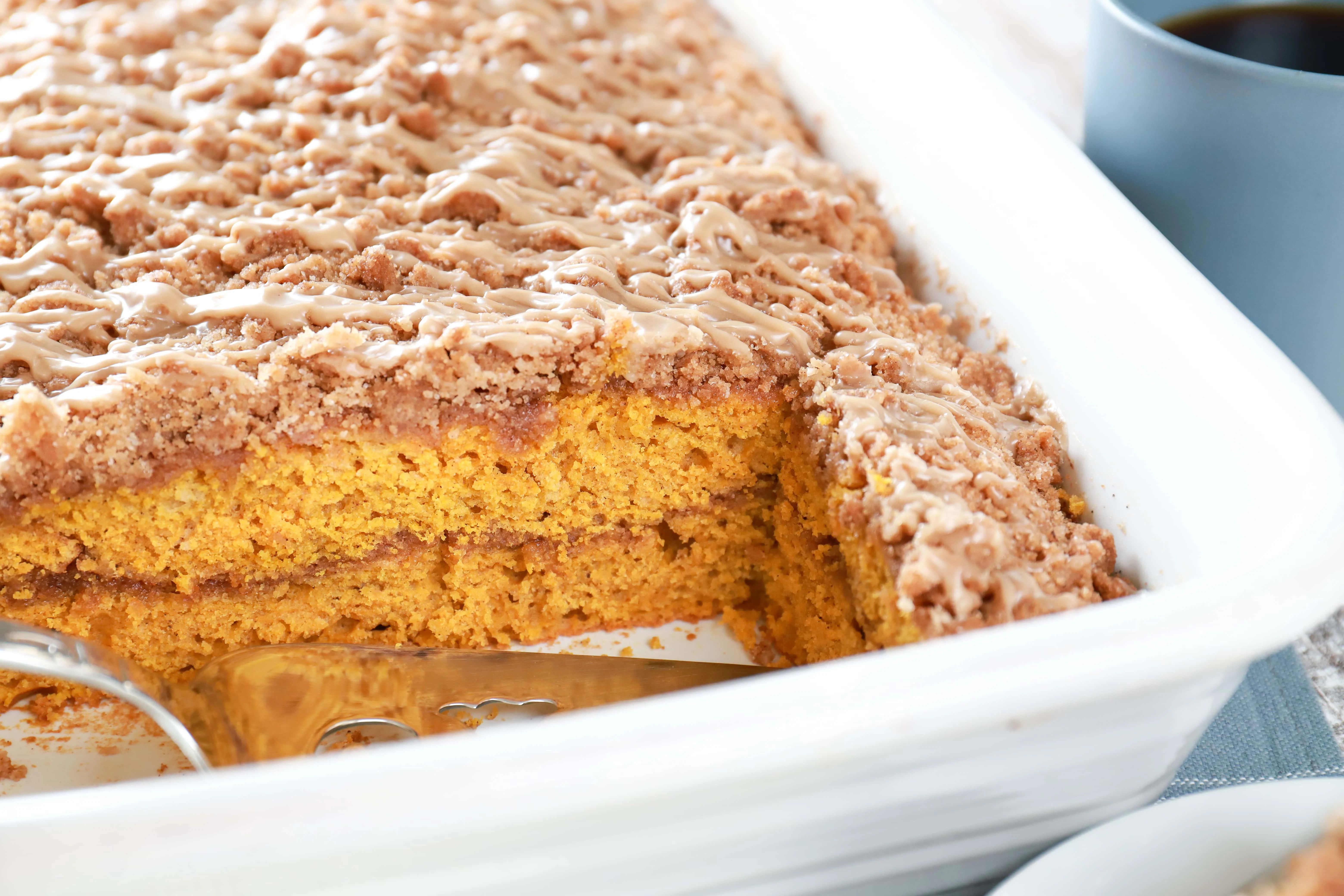 Image of row of maple cinnamon pumpkin coffee cake in cake pan. Recipe from A Kitchen Addiction