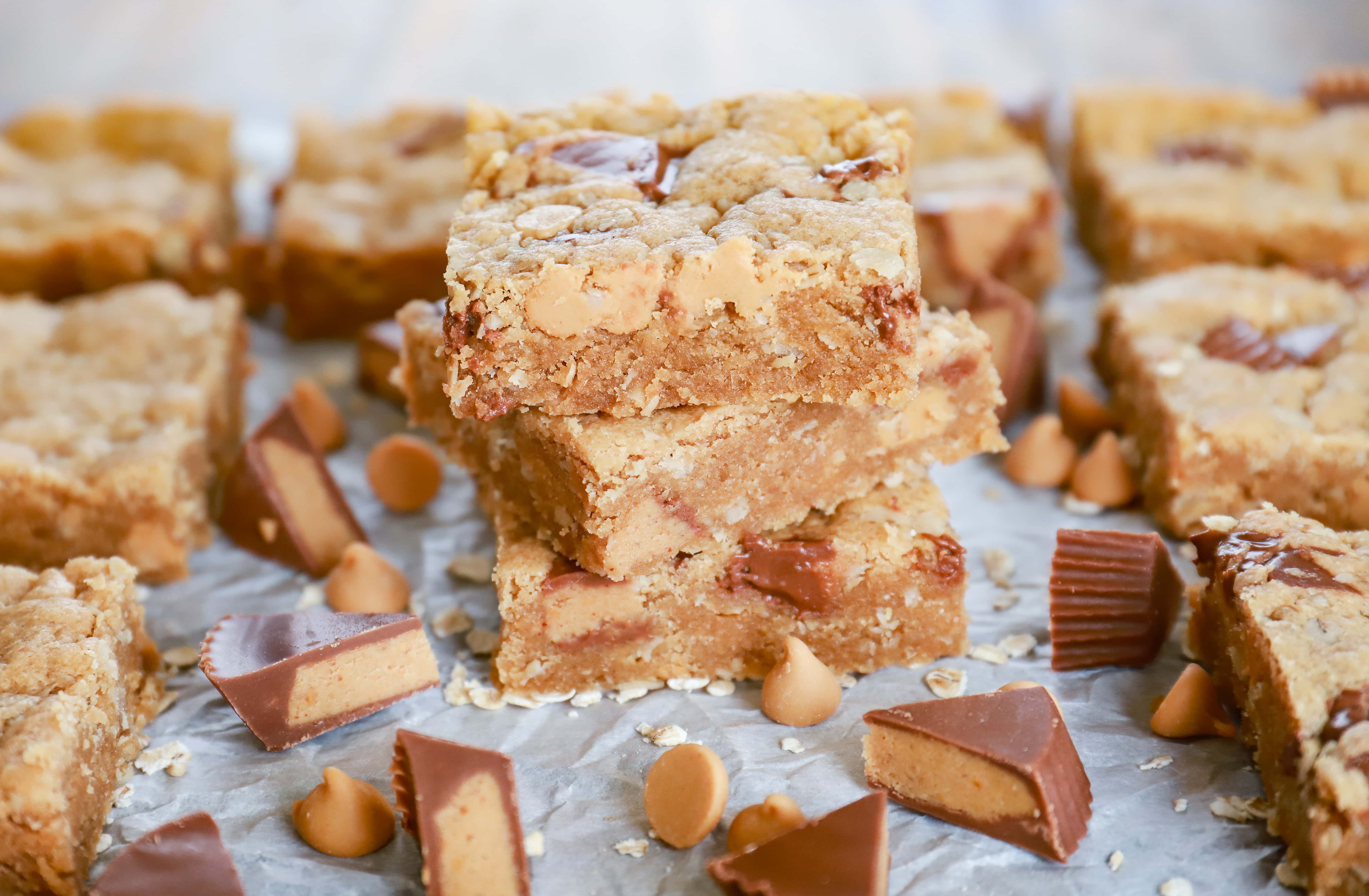 Up close view of a stack of peanut butter overload cookie bars on parchment paper. Recipe from A Kitchen Addiction