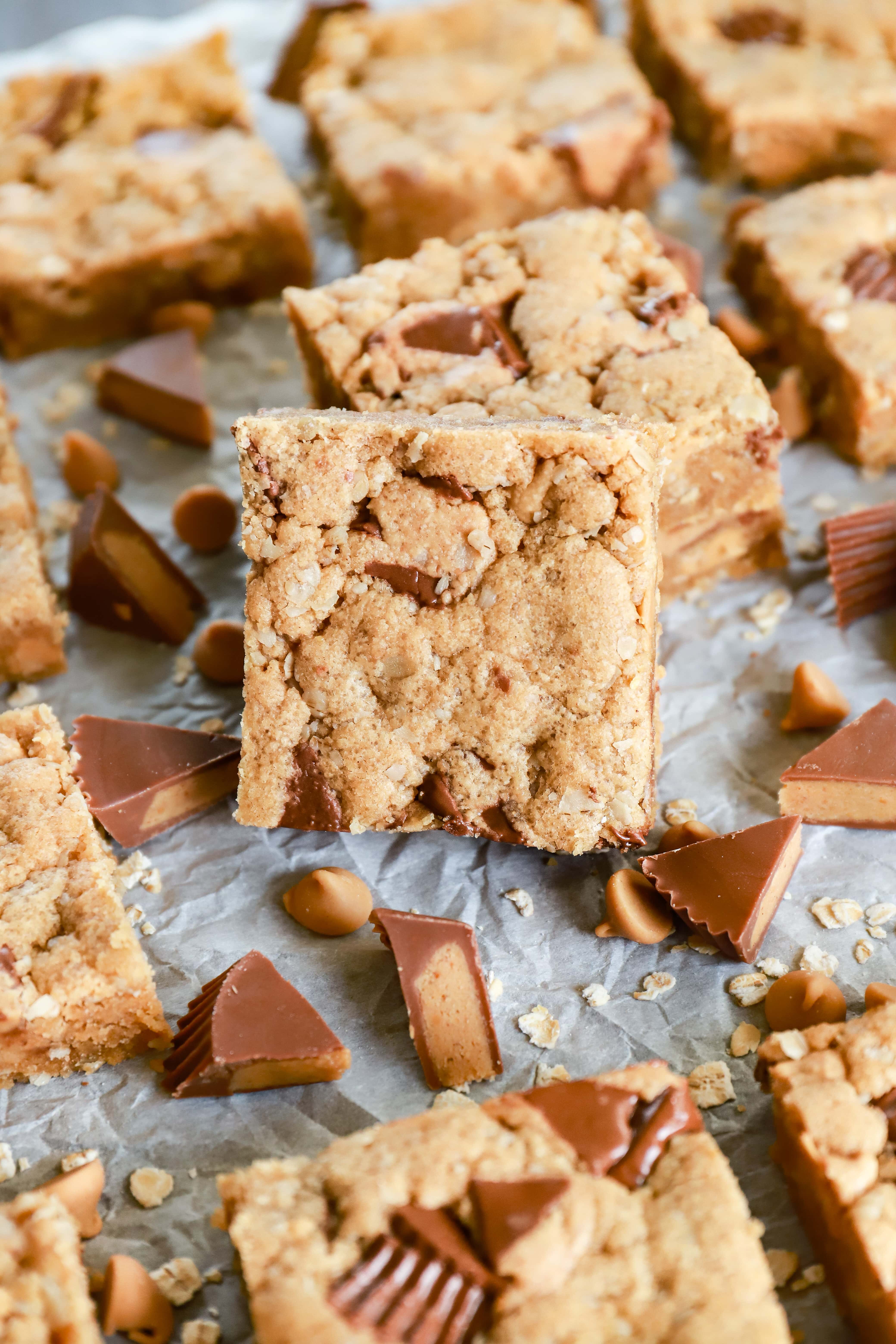 Peanut butter overload cookie bars spread out on parchment paper. Recipe from A Kitchen Addiction.