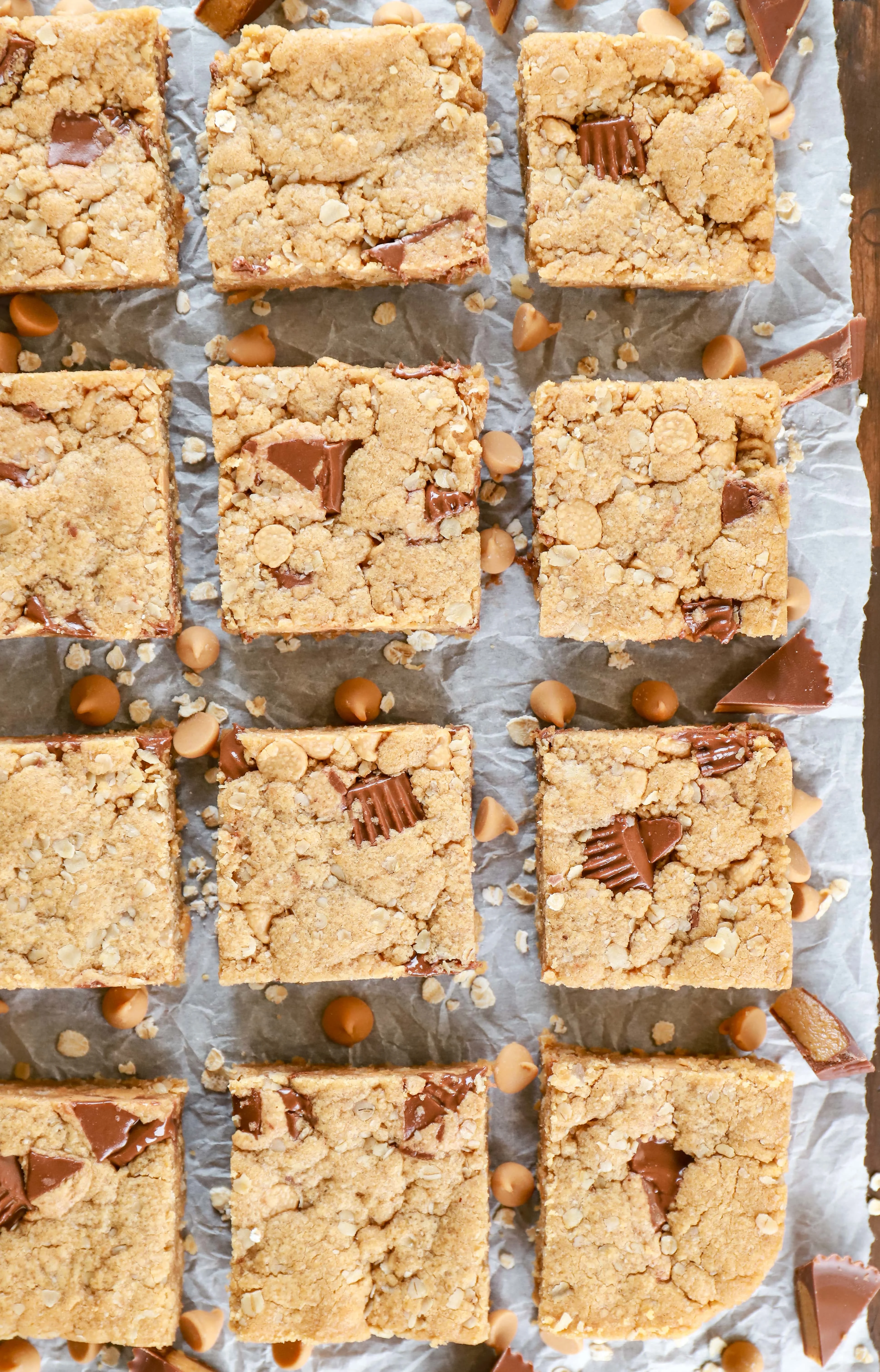Overhead view of peanut butter overload cookie bars on parchment paper. Recipe from A Kitchen Addiction.