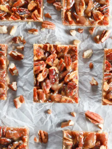 Above view of a batch of honey pecan pie bars cut and arranged on parchment paper