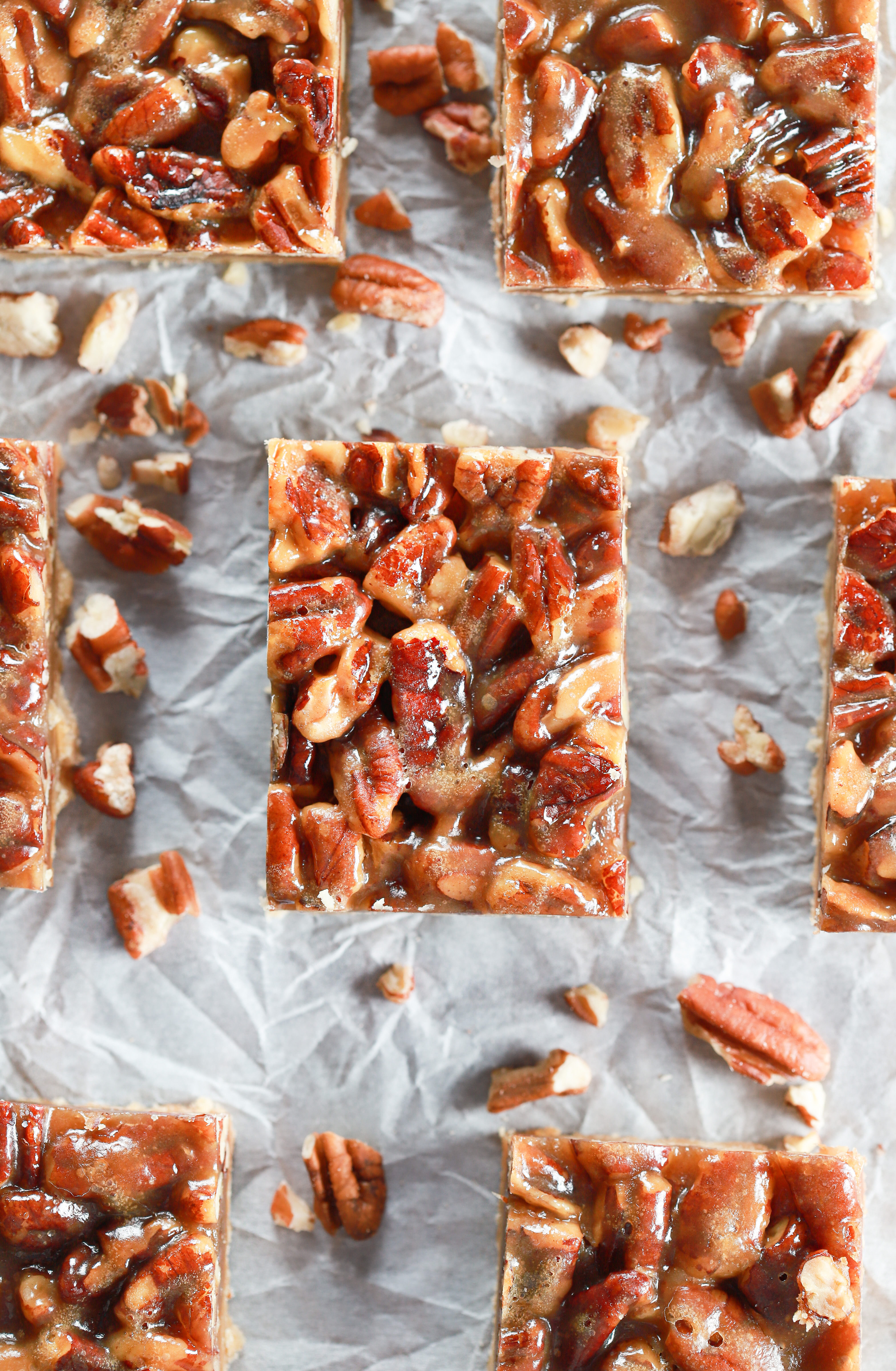 Above view of a batch of honey pecan pie bars cut and arranged on parchment paper