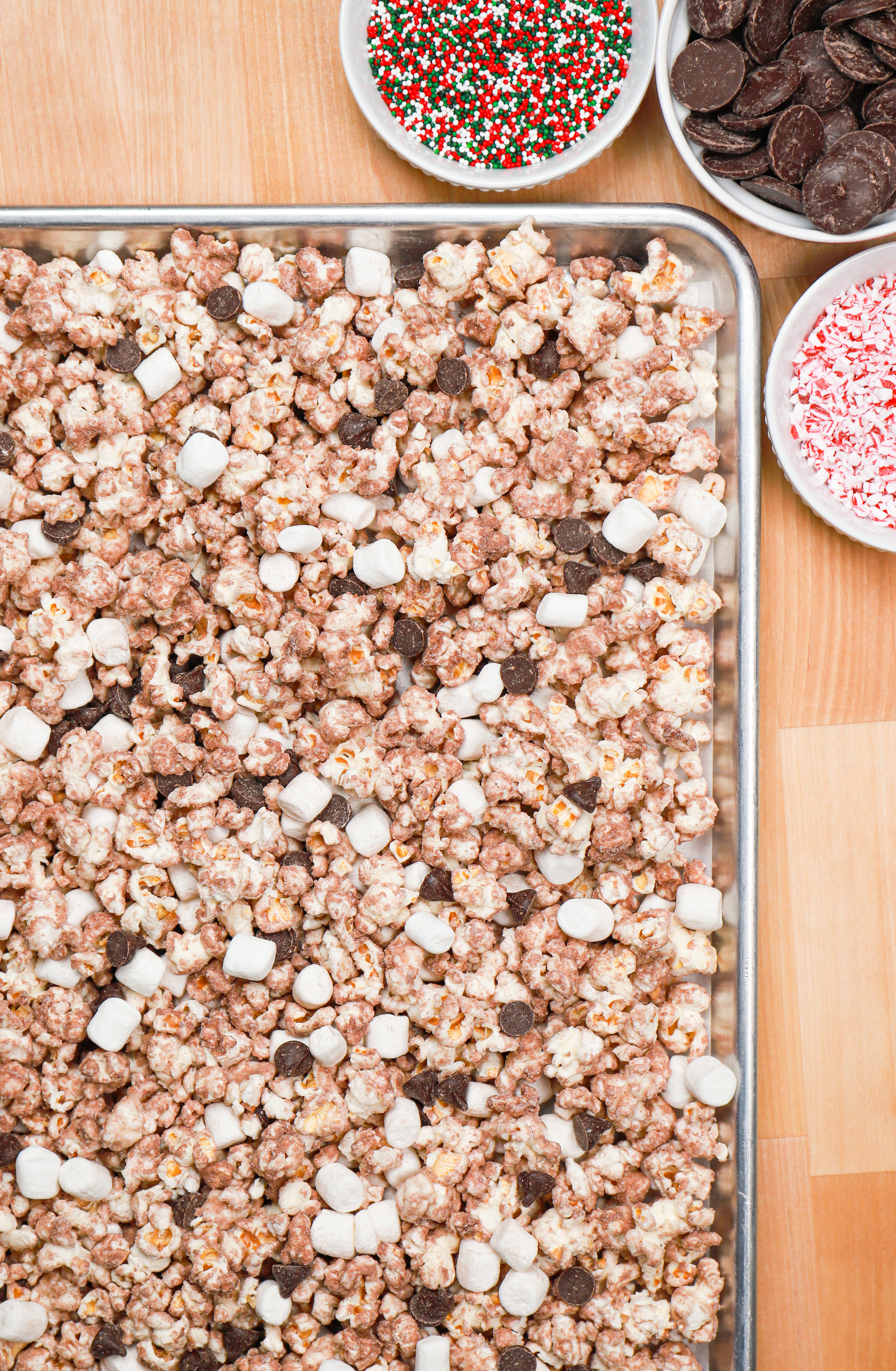 Overhead view of hot chocolate popcorn on a rimmed baking sheet before adding toppings.
