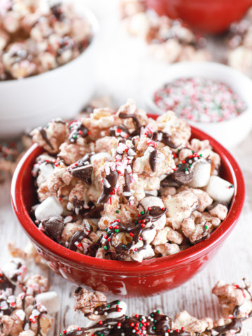 Hot chocolate popcorn in a small red bowl with popcorn surrounding the bowl.