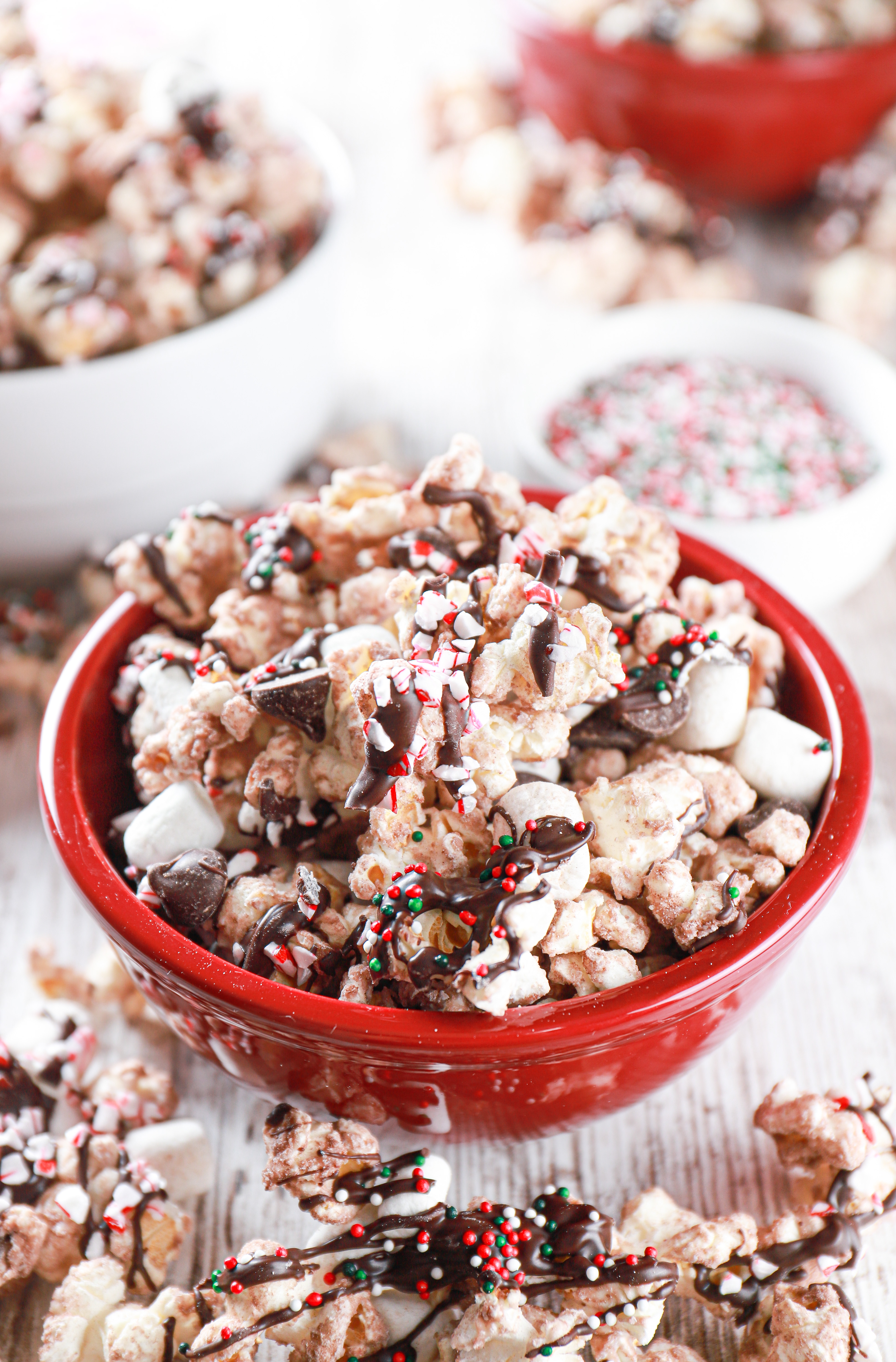 Hot chocolate popcorn in a small red bowl with popcorn surrounding the bowl.
