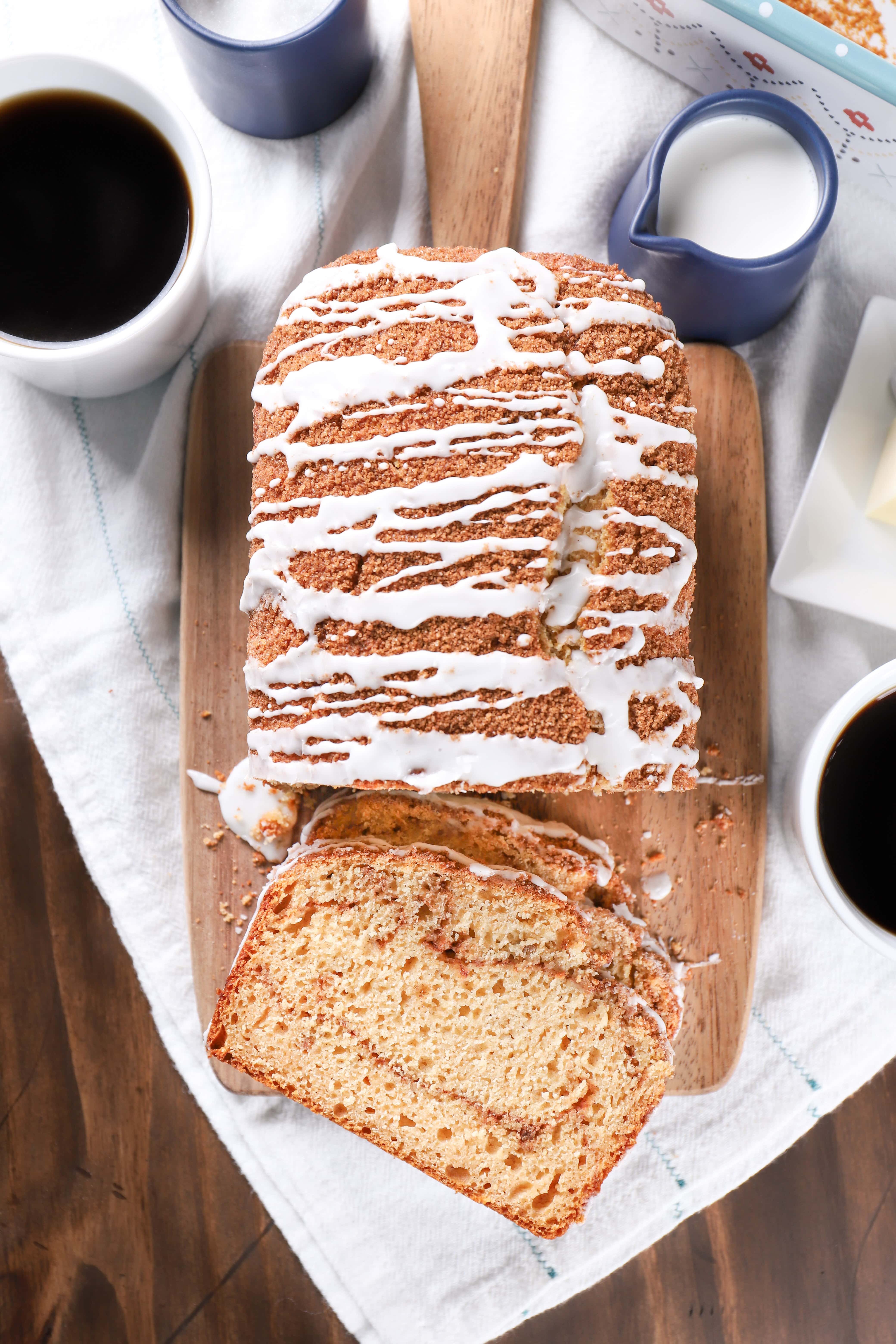 Cinnamon Swirl Yogurt Quick Bread on a cutting board with cups of coffee. Recipe for quick bread from A Kitchen Addiction.