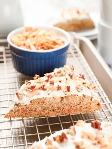 Side view of a frosted carrot cake scone sitting on a cooling rack. Recipe from A Kitchen Addiction