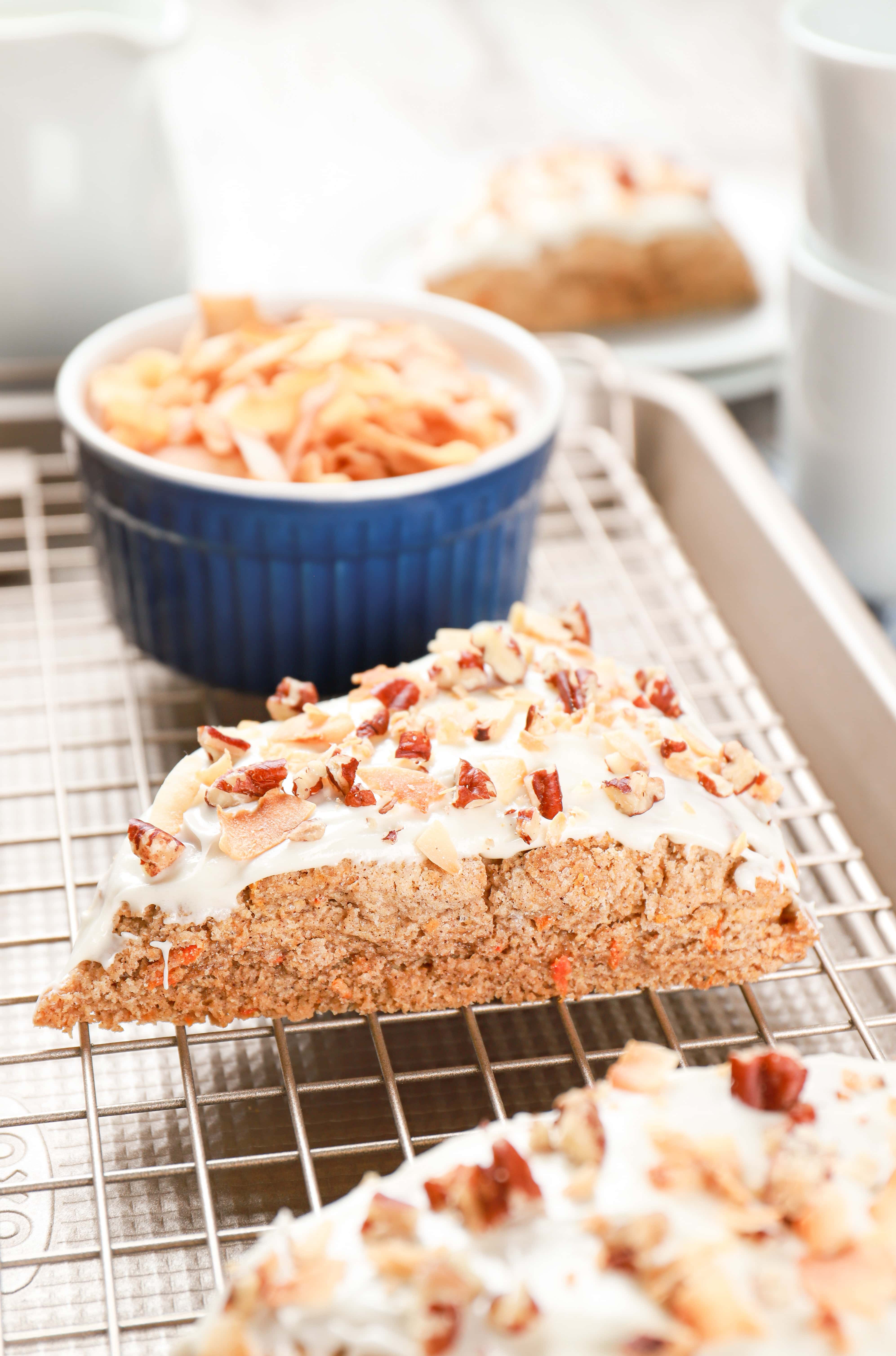 Side view of a frosted carrot cake scone sitting on a cooling rack. Recipe from A Kitchen Addiction