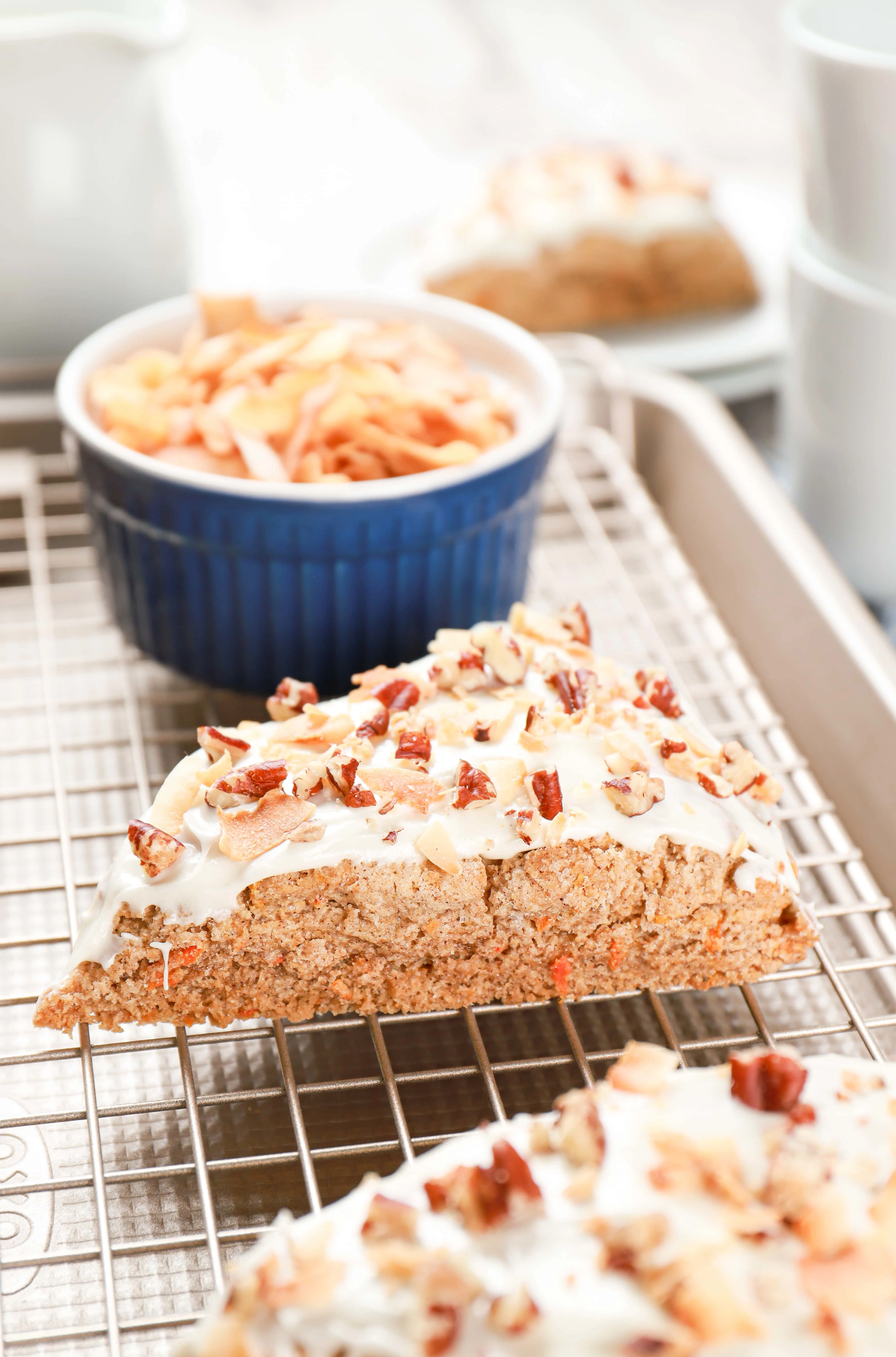 Side view of a frosted carrot cake scone sitting on a cooling rack. Recipe from A Kitchen Addiction