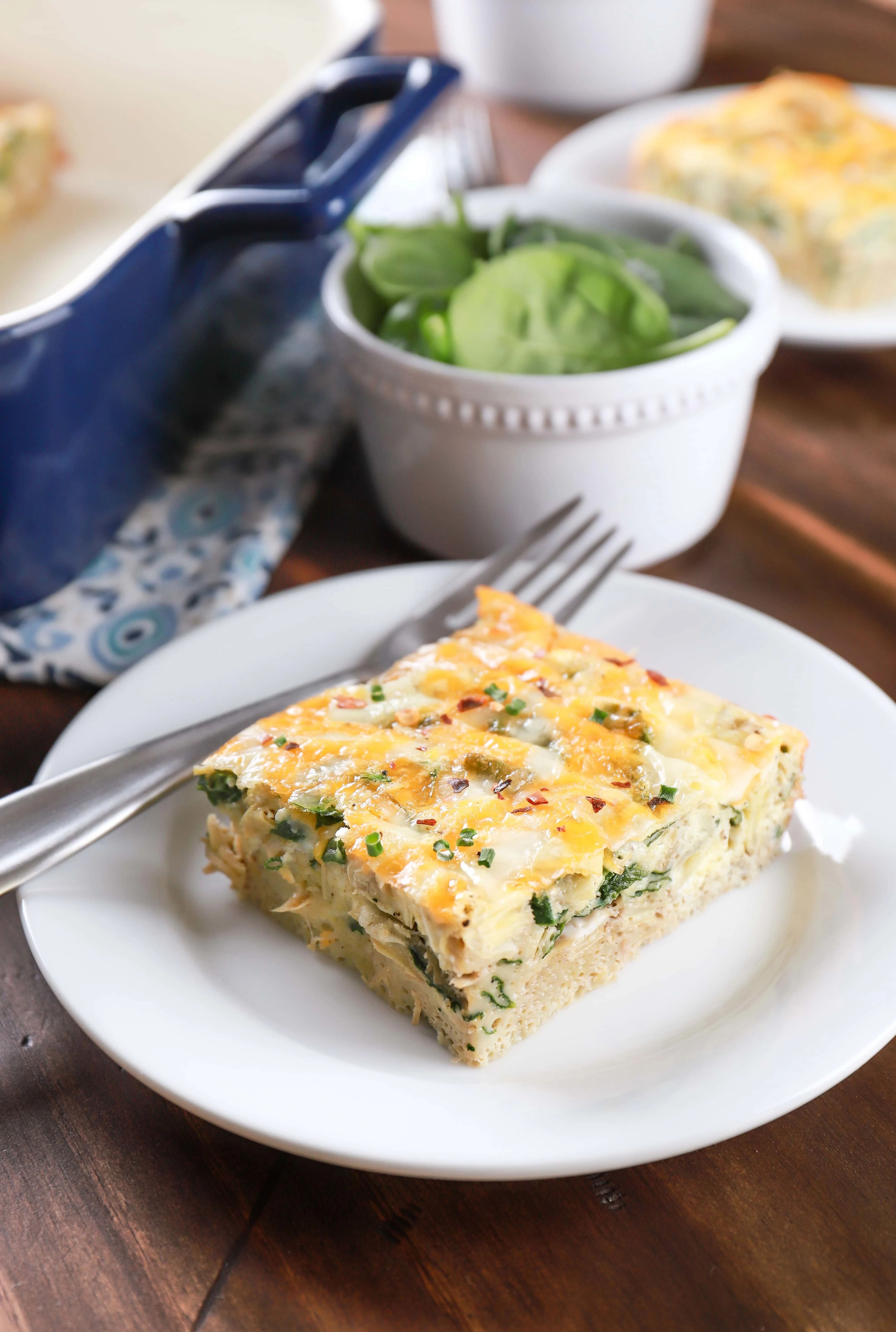 Two plates of cheesy spinach artichoke egg bake. Recipe from A Kitchen Addiction