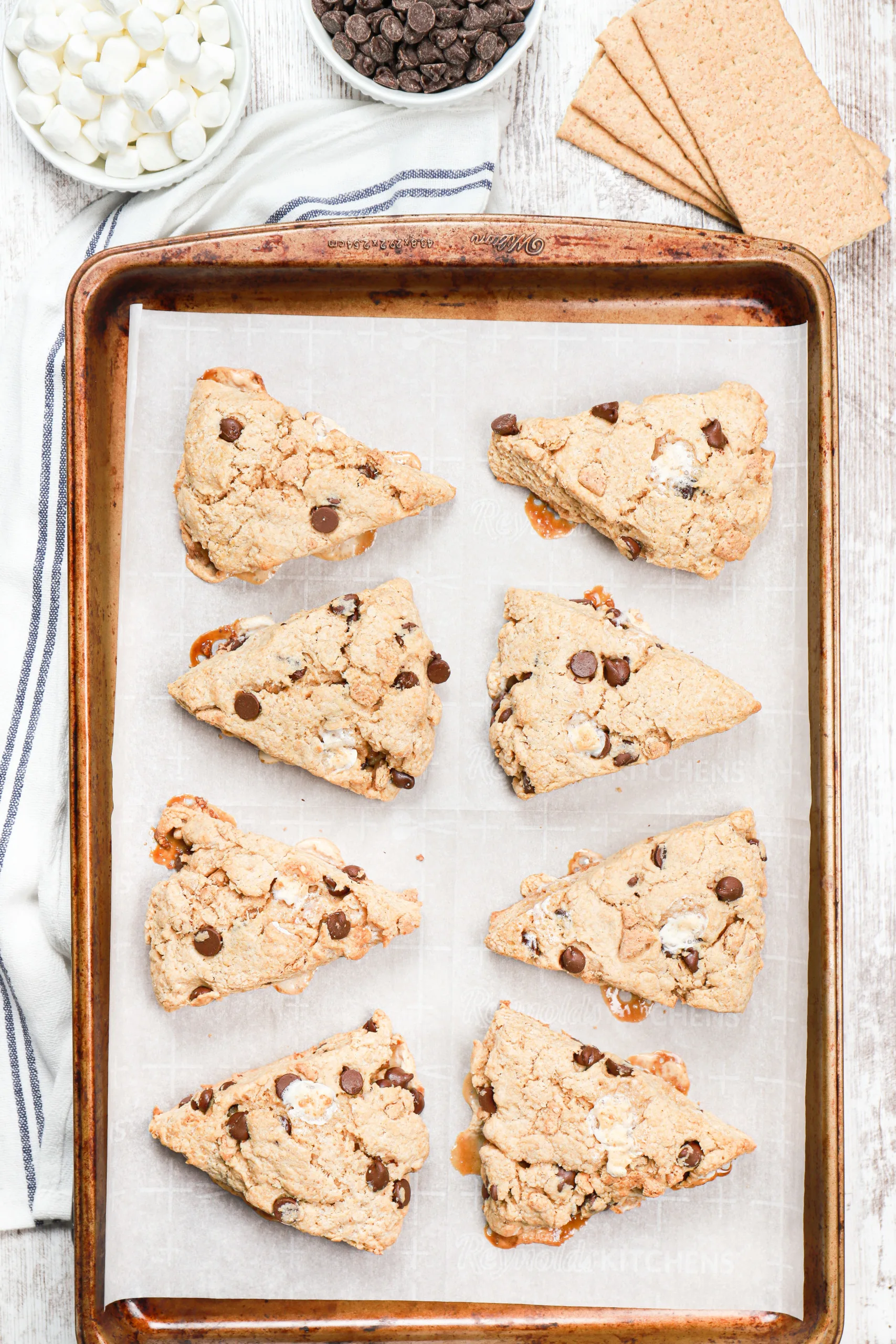 Overhead view of the s'mores scones on a baking sheet before the toppings have been drizzled over the tops.