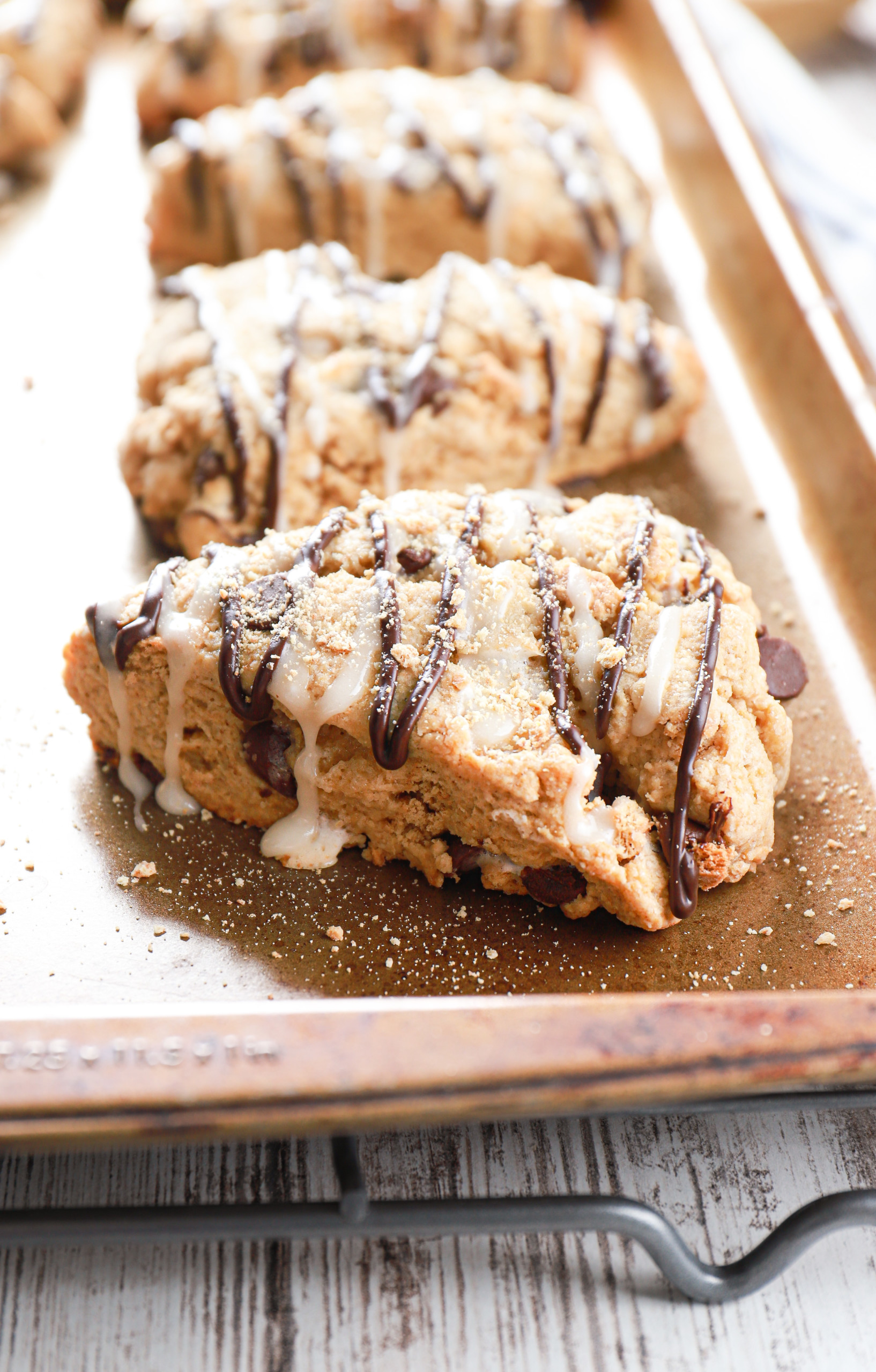 Side view of a batch of s'mores scones on a baking sheet atop a wire cooling rack.