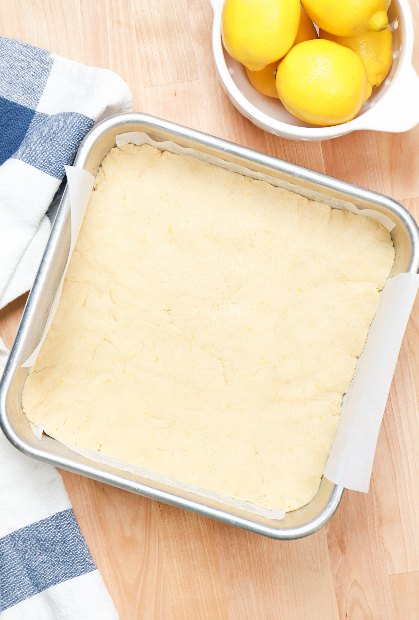 Lemon sugar cookie bar dough in aluminum baking pan before baking.