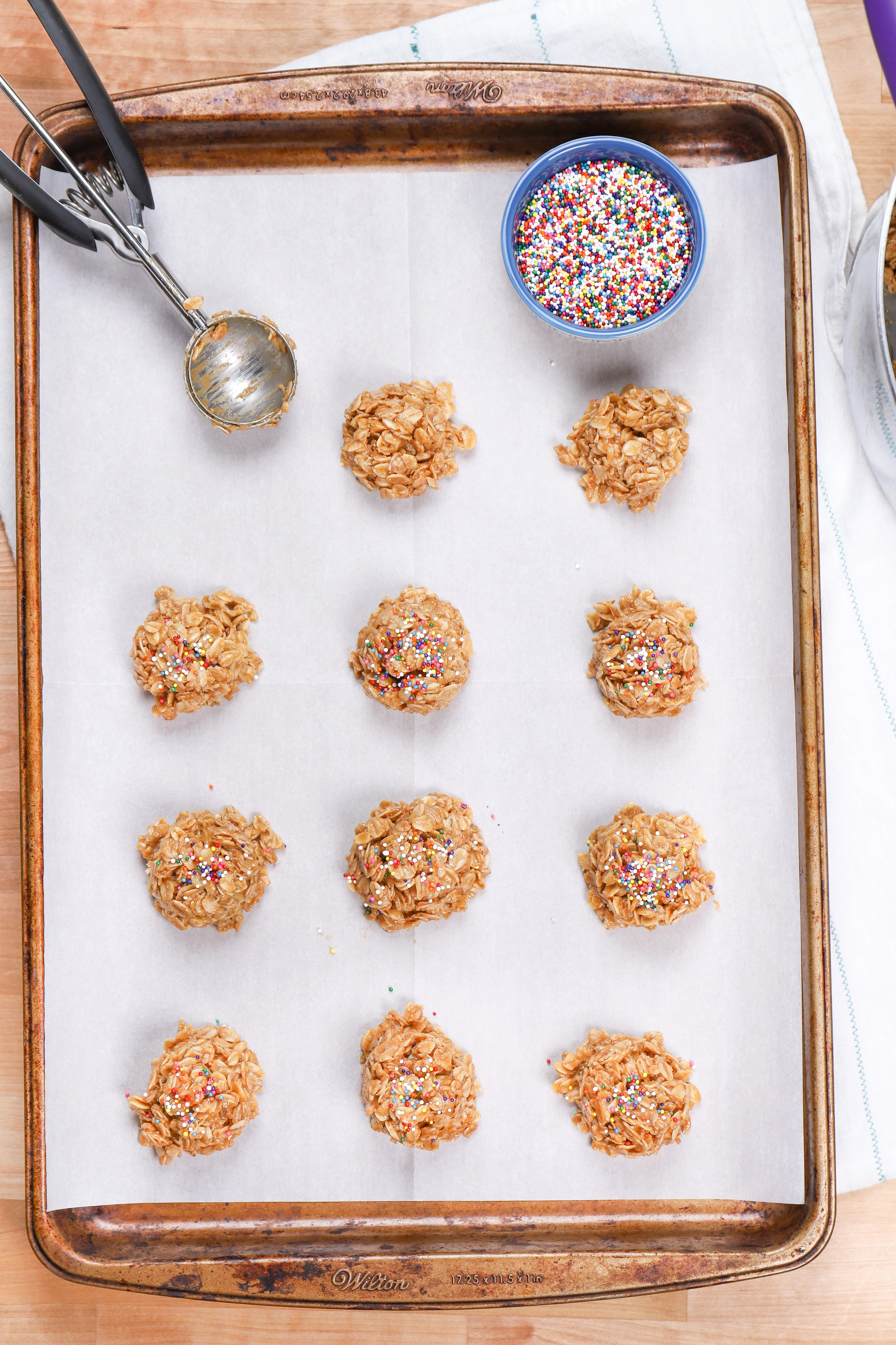Putting peanut butter no bake cookies on a baking sheet with a cookie scoop