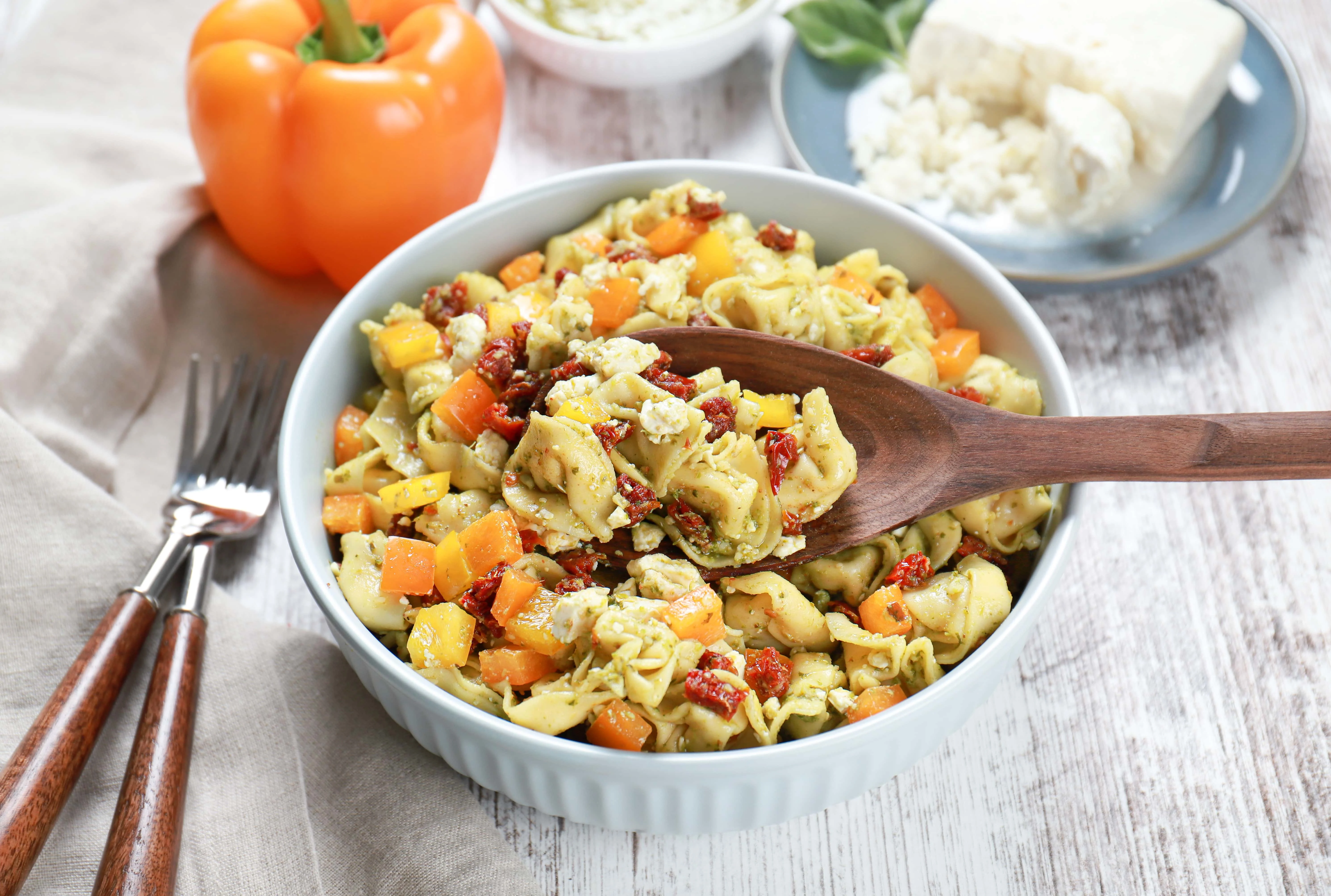 Above view of a wooden spoon full of pesto tortellini pasta salad.