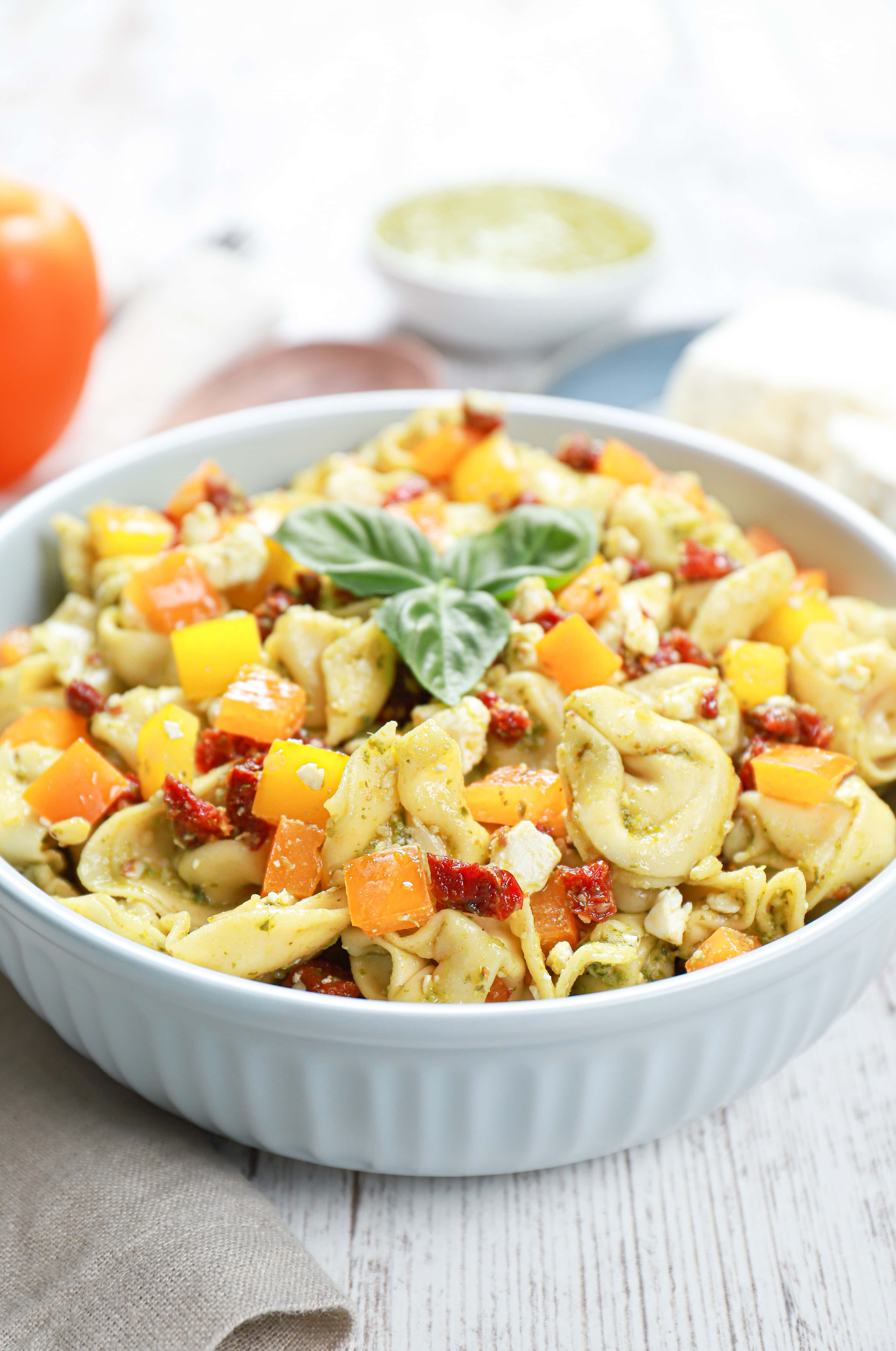 Side view of a blue bowl filled with pesto pasta salad.