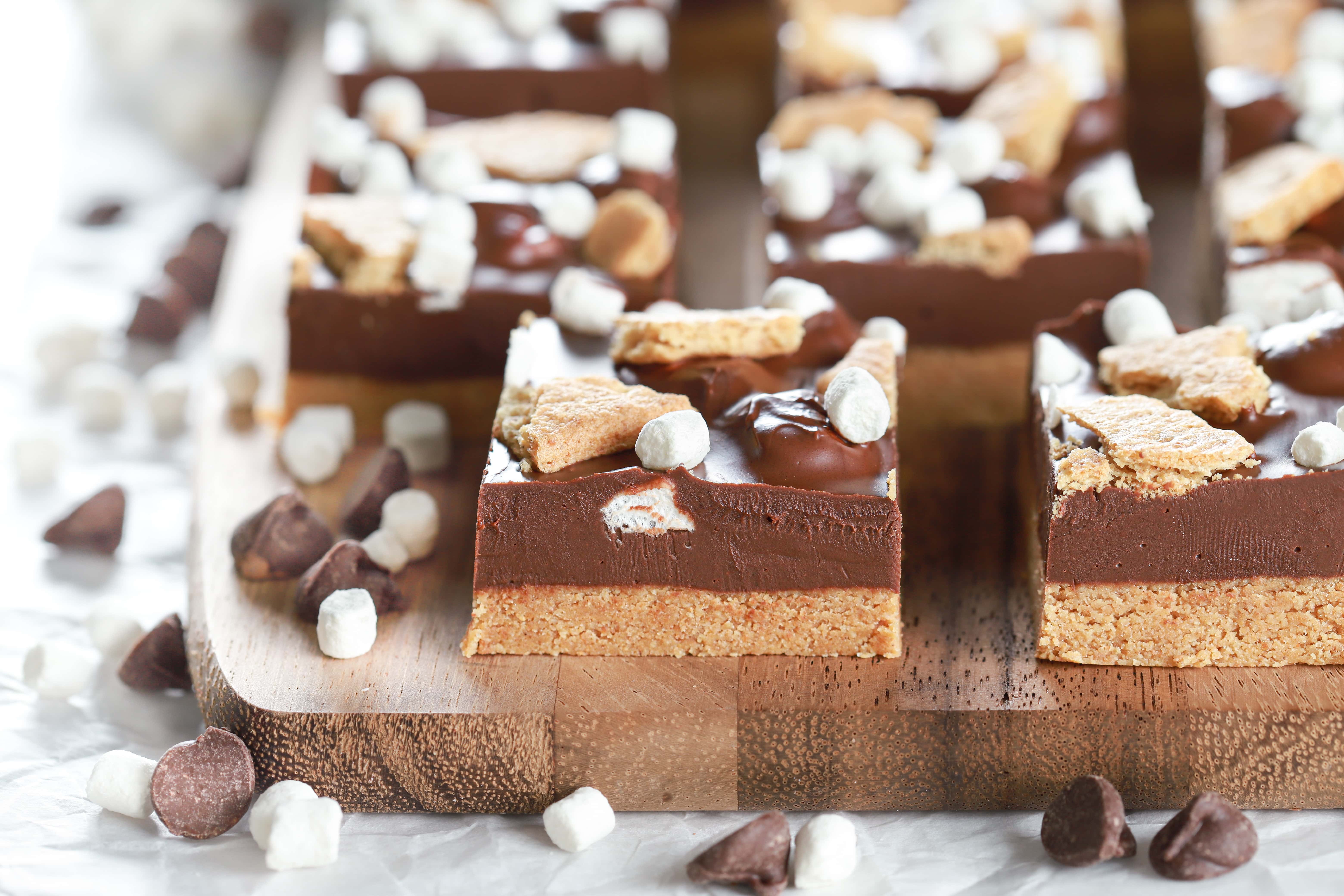 Up close side view of a no bake peanut butter smores bar on a wooden cutting board. Recipe for bars from A Kitchen Addiction