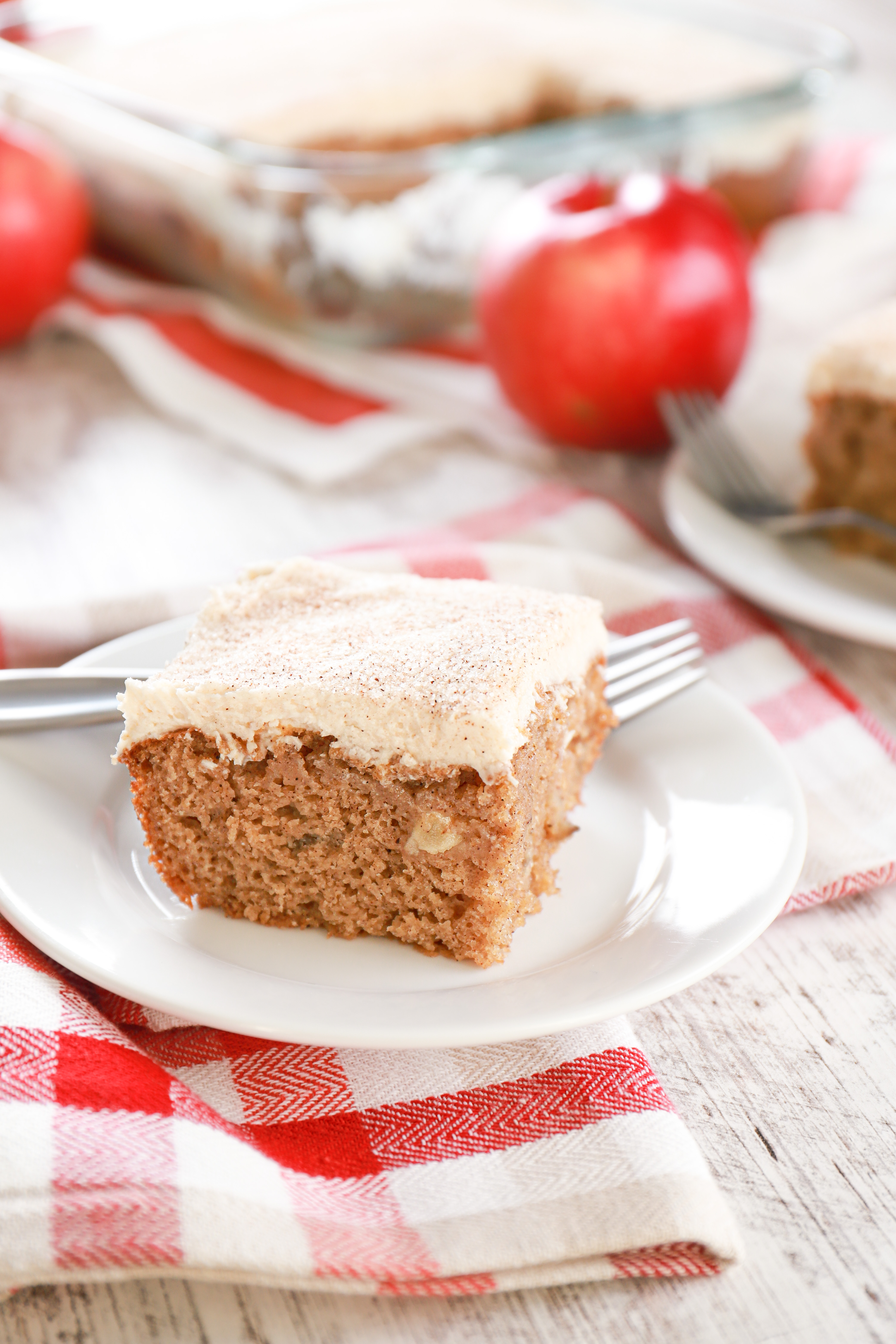 slice of maple buttercream frosted apple cake on a small white plate