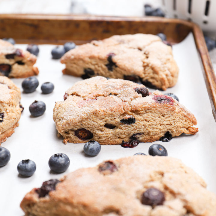 Side view of a blueberry snickerdoodle scone on a parchment paper lined baking sheet.