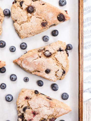 Up close overhead view of a few blueberry snickerdoodle scones on a parchment paper lined baking sheet.