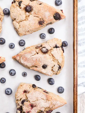 Up close overhead view of a few blueberry snickerdoodle scones on a parchment paper lined baking sheet.