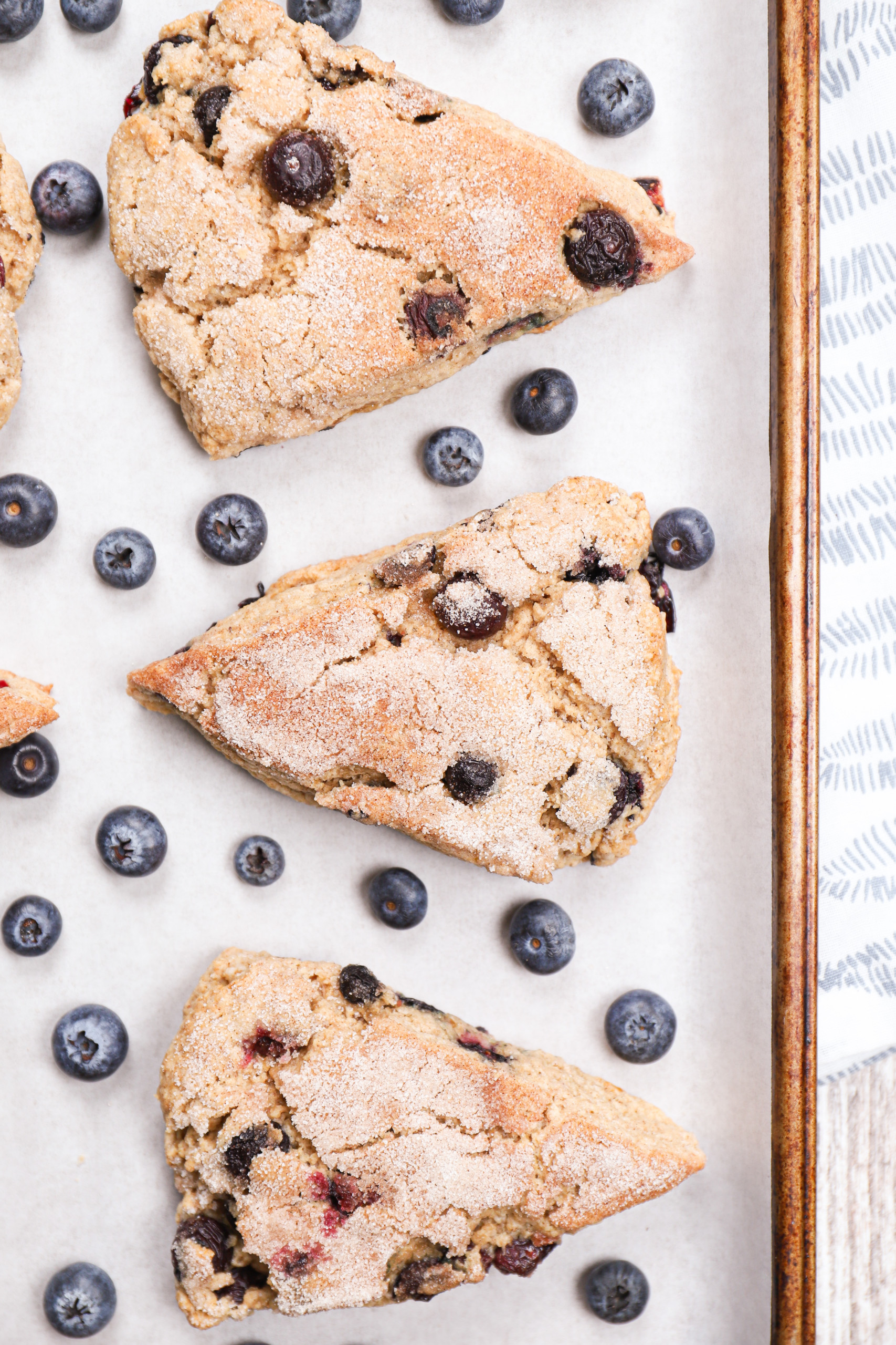 Up close overhead view of a few blueberry snickerdoodle scones on a parchment paper lined baking sheet.