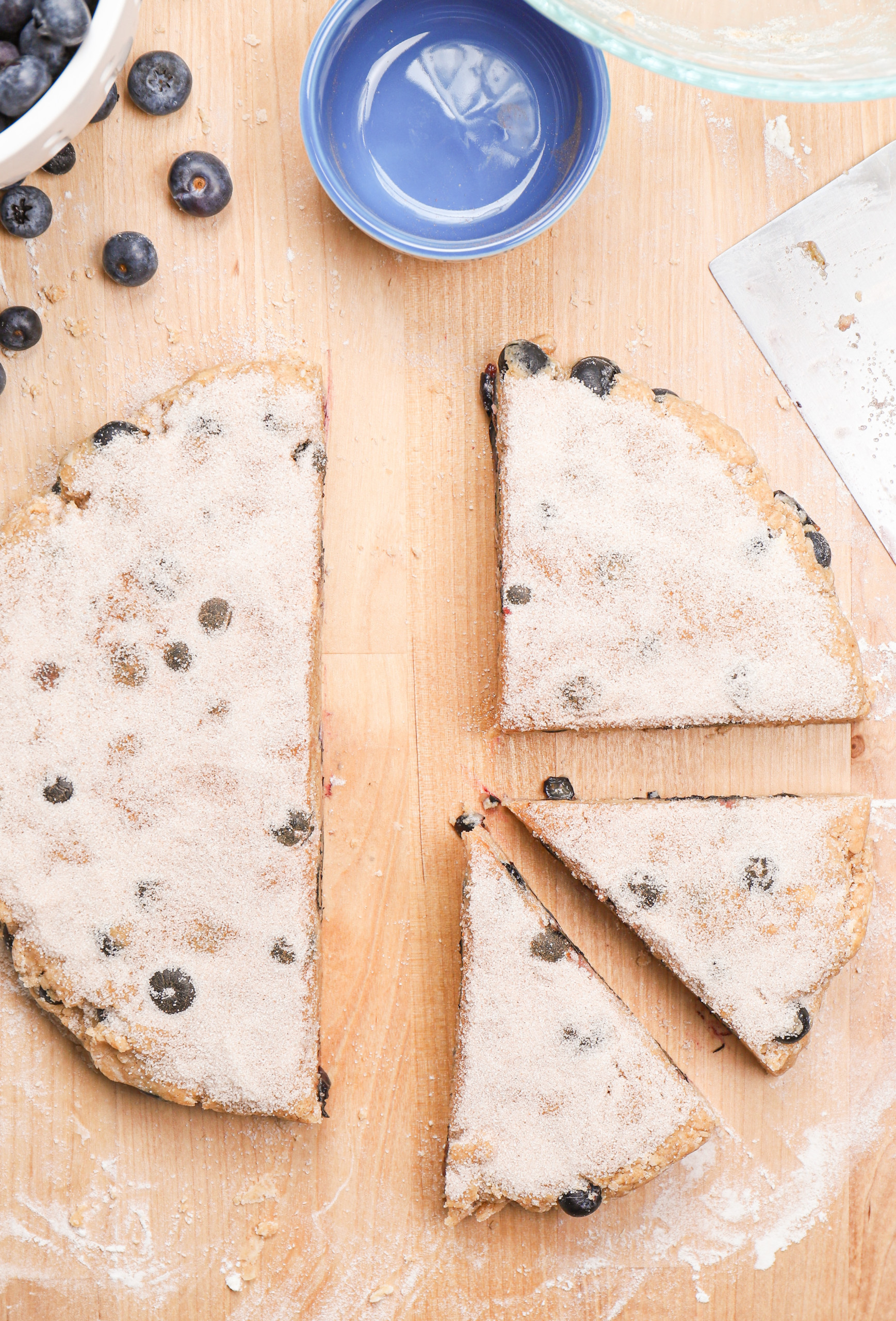 Blueberry snickerdoodle scone dough with cinnamon sugar topping cut into pieces.