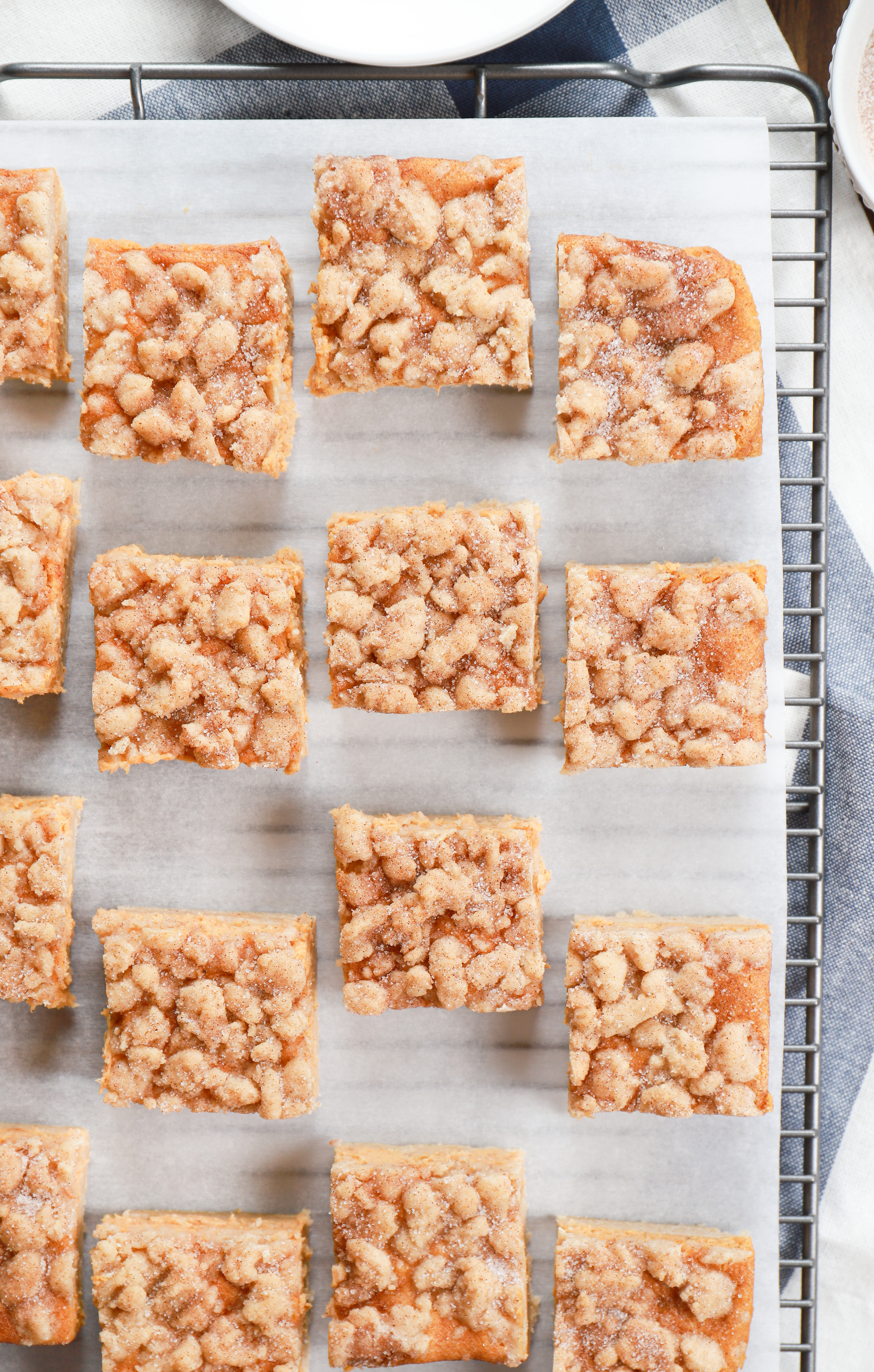 Overhead view of a batch of pumpkin snickerdoodle cheesecake bars on a cooling rack.