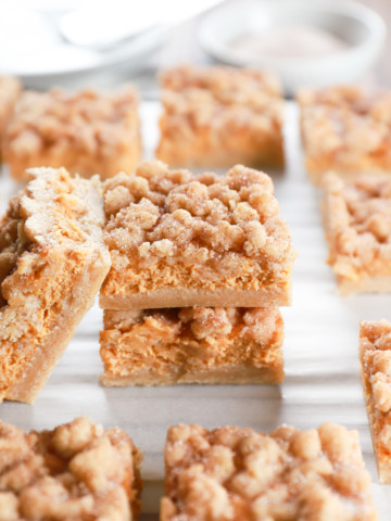 Stacked pumpkin snickerdoodle cheesecake bars on a cooling rack