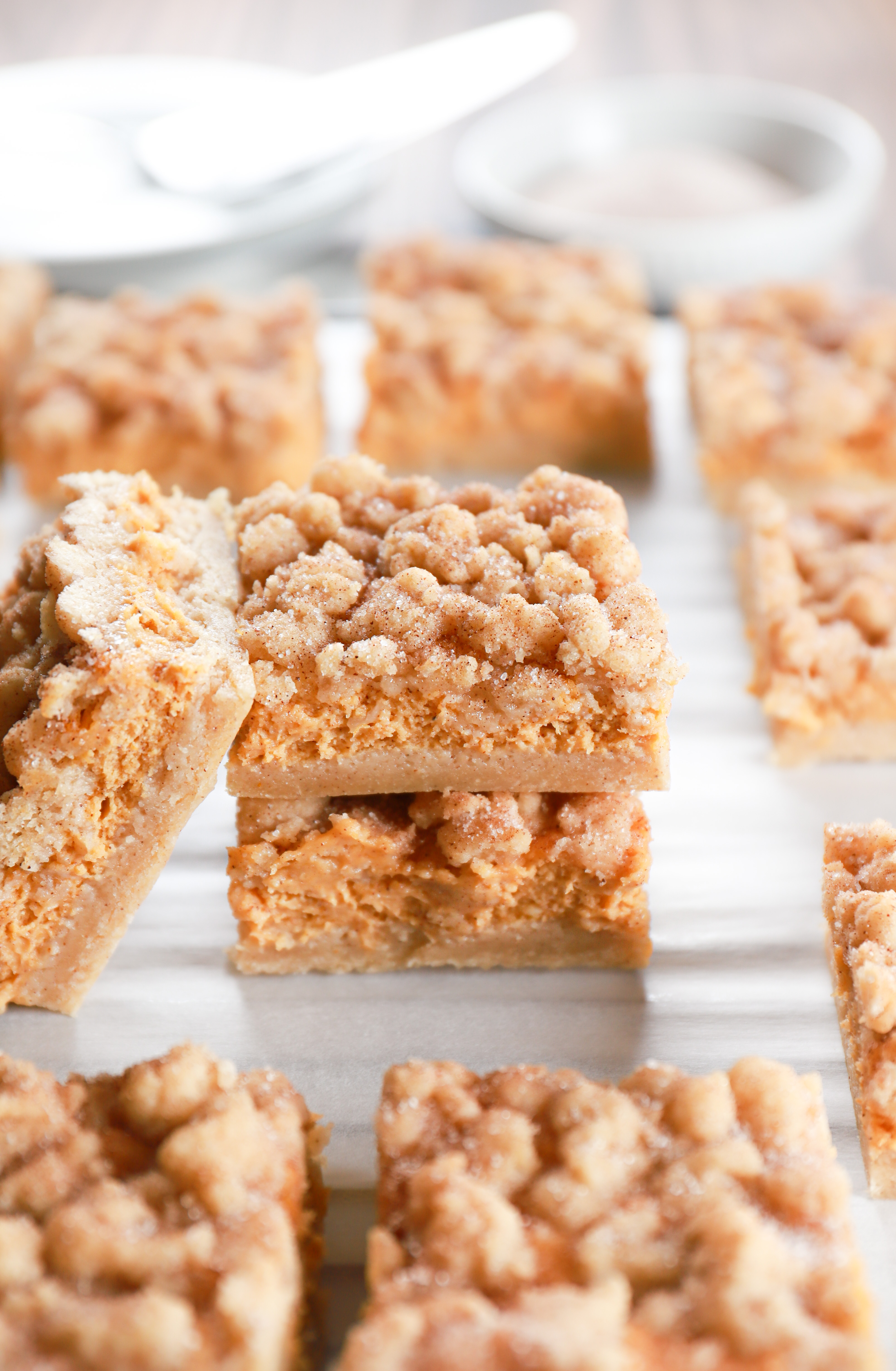 Stacked pumpkin snickerdoodle cheesecake bars on a cooling rack