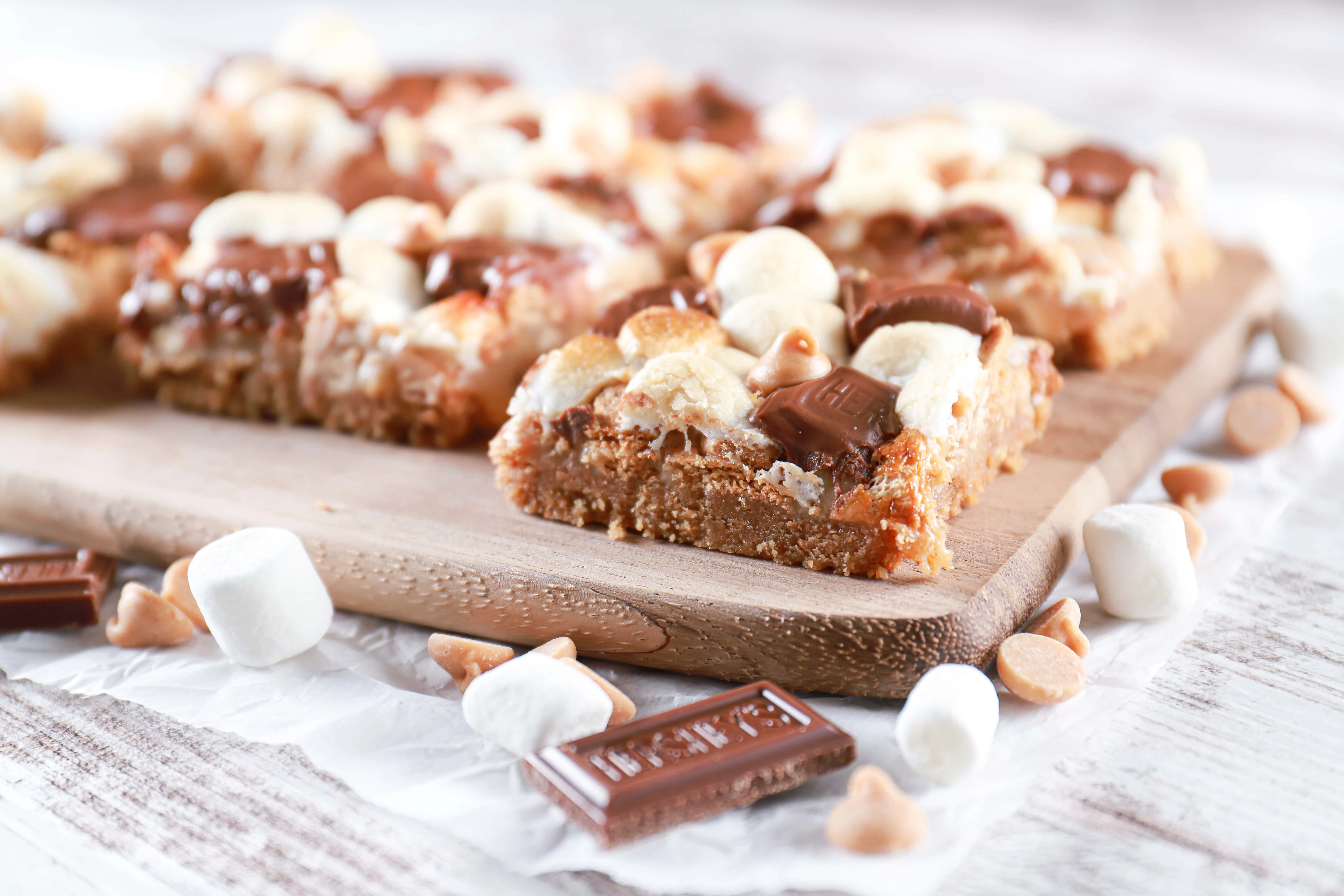 Peanut butter smores seven layer bars on a wooden cutting board. Recipe from A Kitchen Addiction