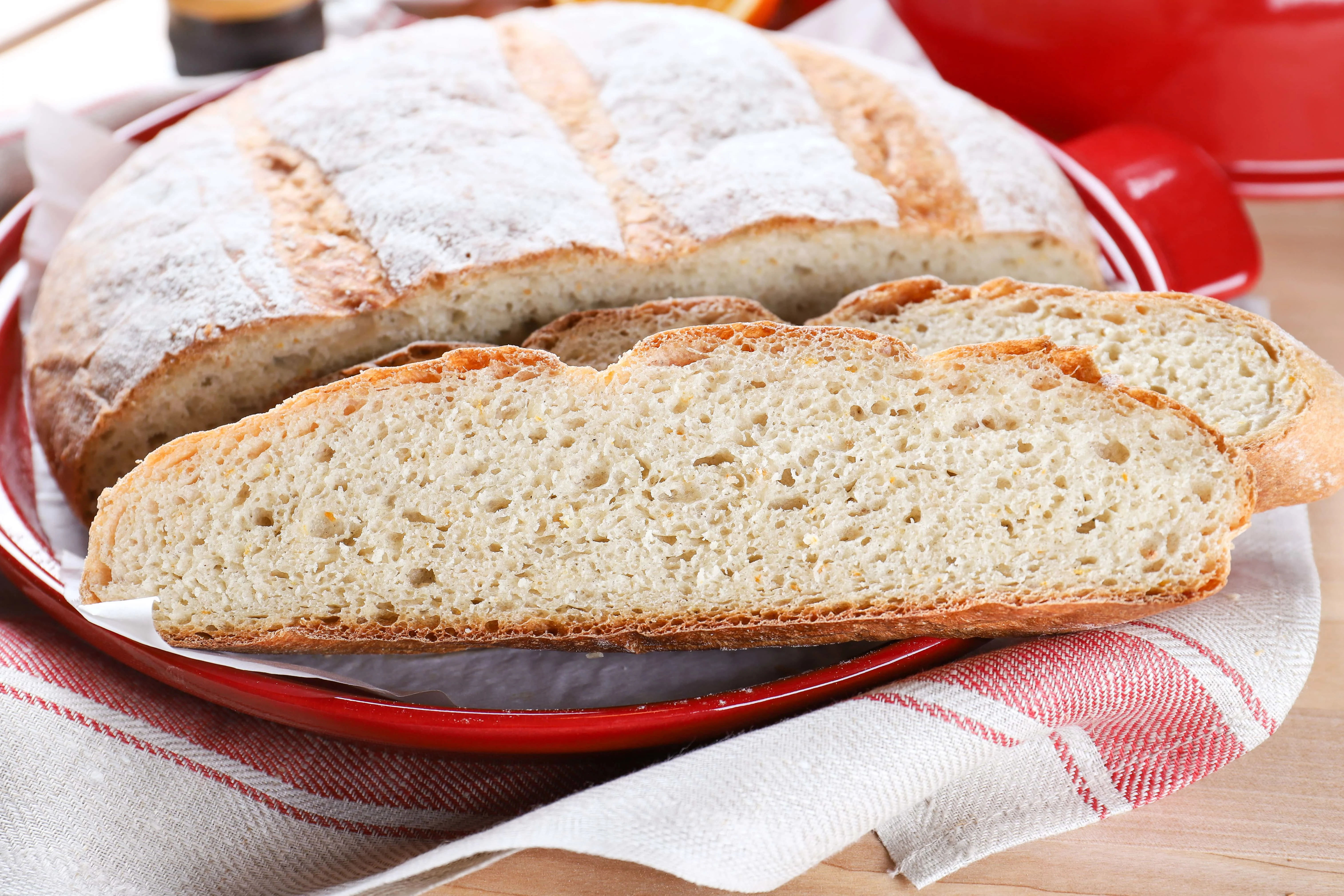 slices of artisan orange cardamom bread on the base of an Emile Henry bread cloche