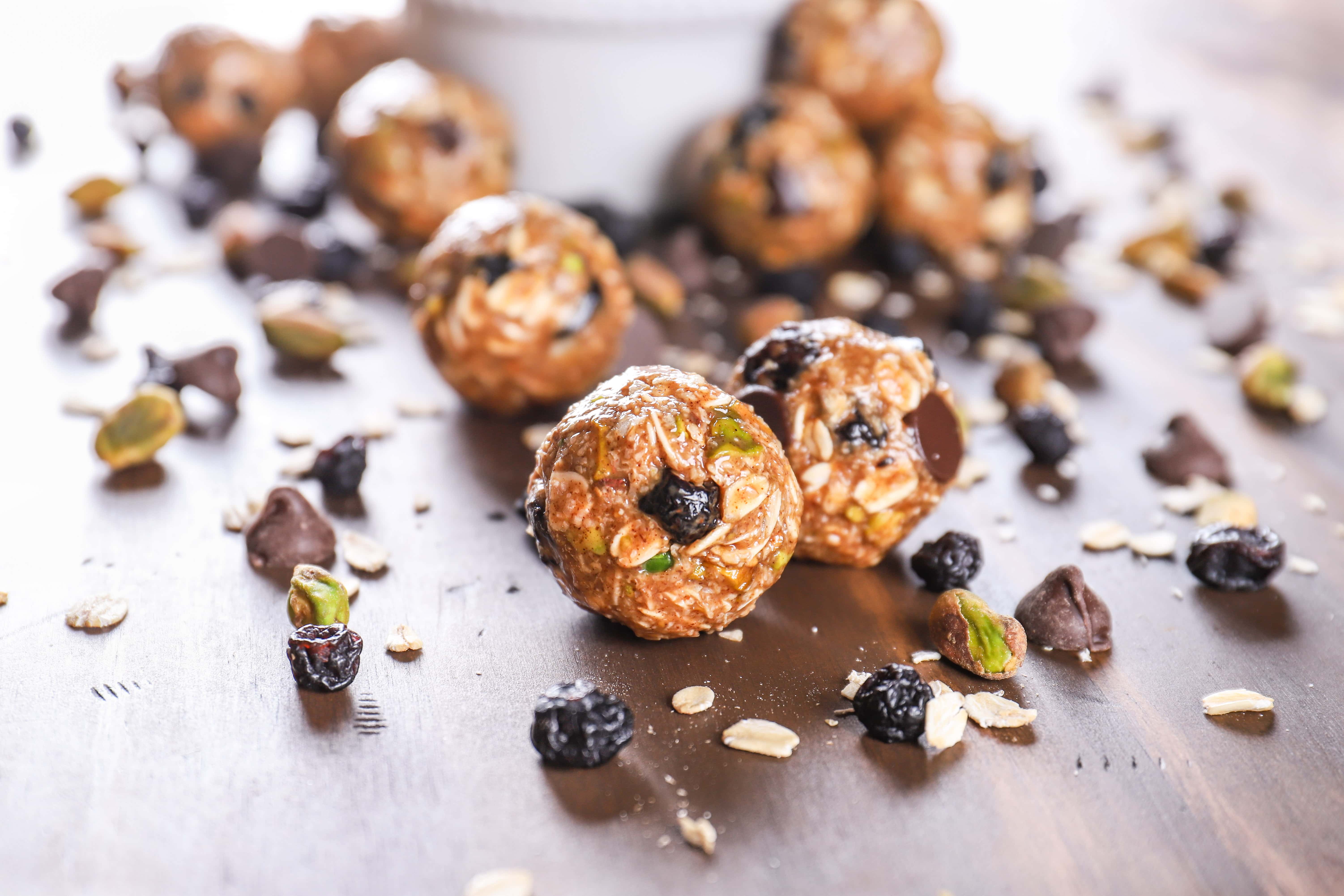 dark chocolate blueberry pistachio granola bites on a table with a bowl of granola bites in the background