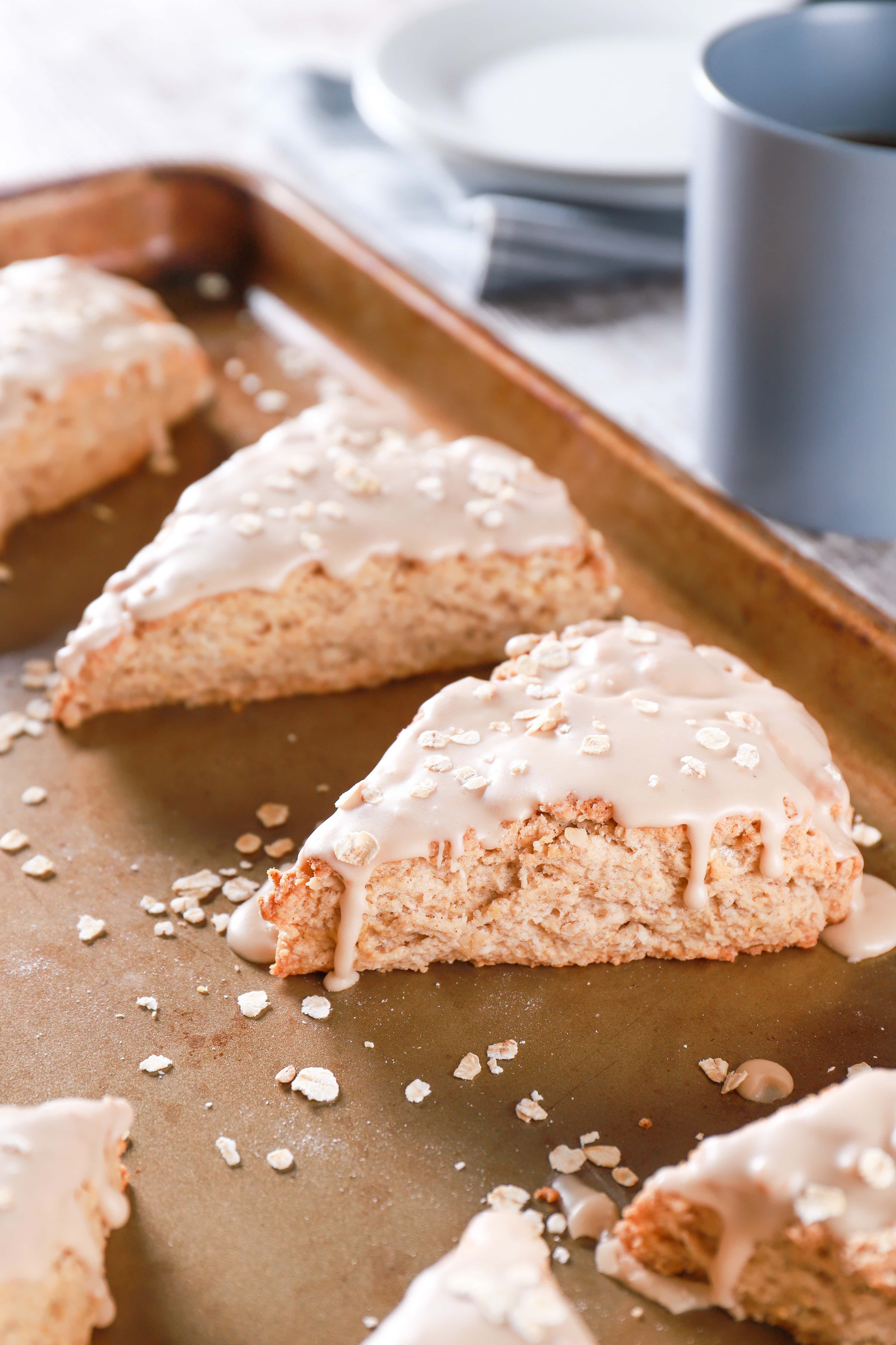 Maple oat scone on a baking sheet with a cup of coffee in the background. Recipe from A Kitchen Addiction