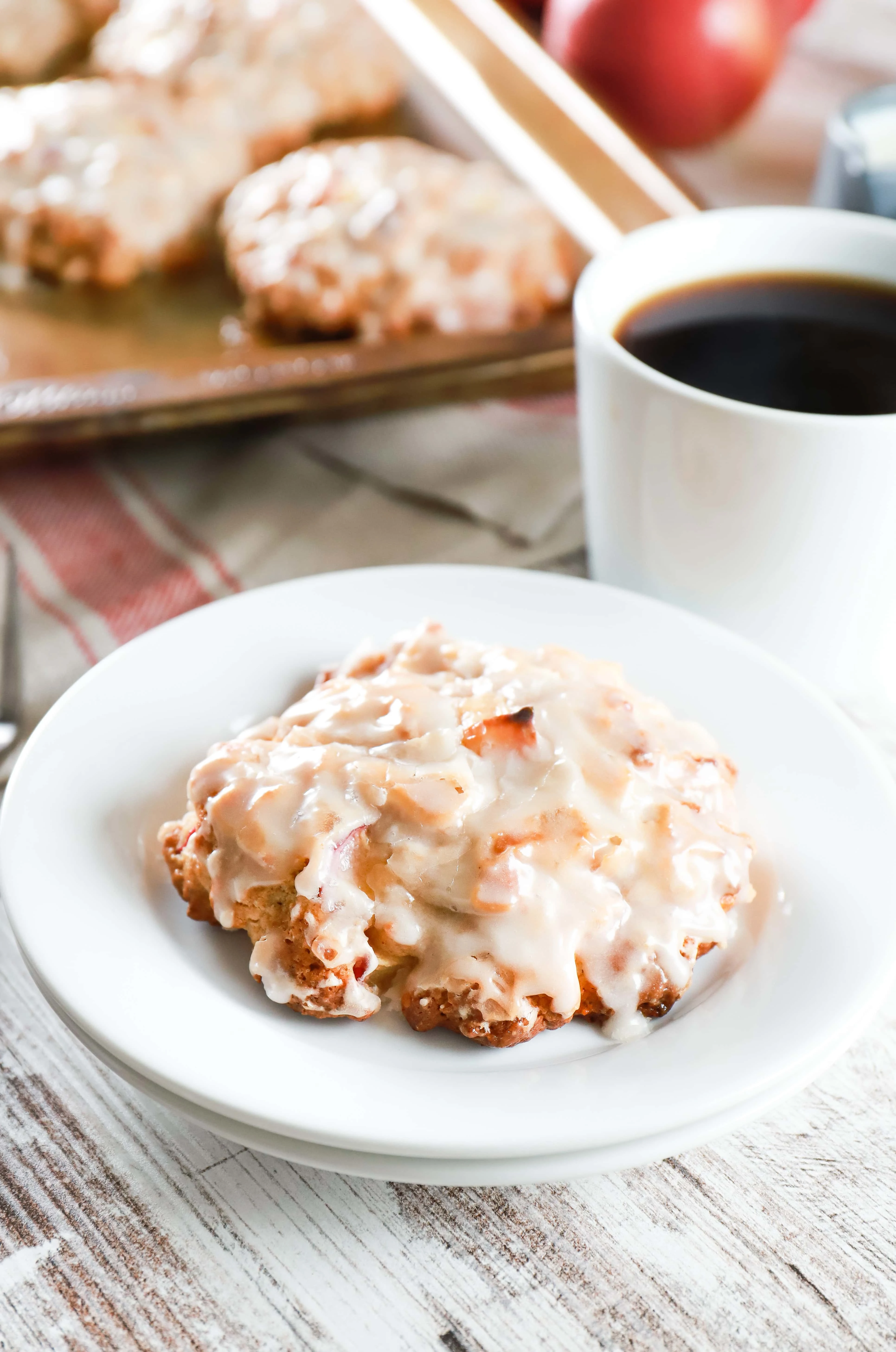 Baked apple fritter on a small white plate next to a cup of coffee. Recipe from A Kitchen Addiction