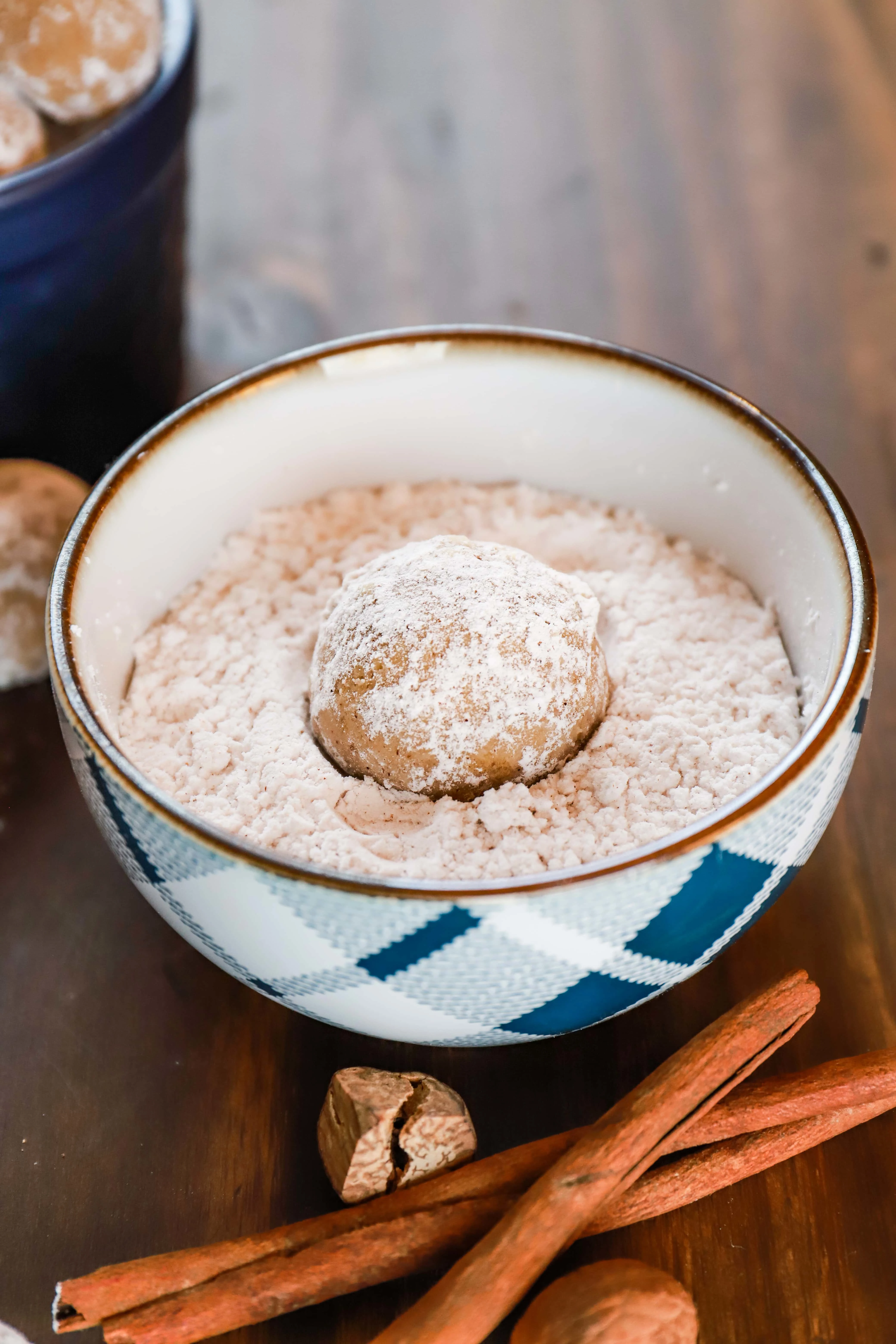 Overhead view of a gingerbread snowball cookie in a dish filled with confectioner's sugar. Recipe from A Kitchen Addiction