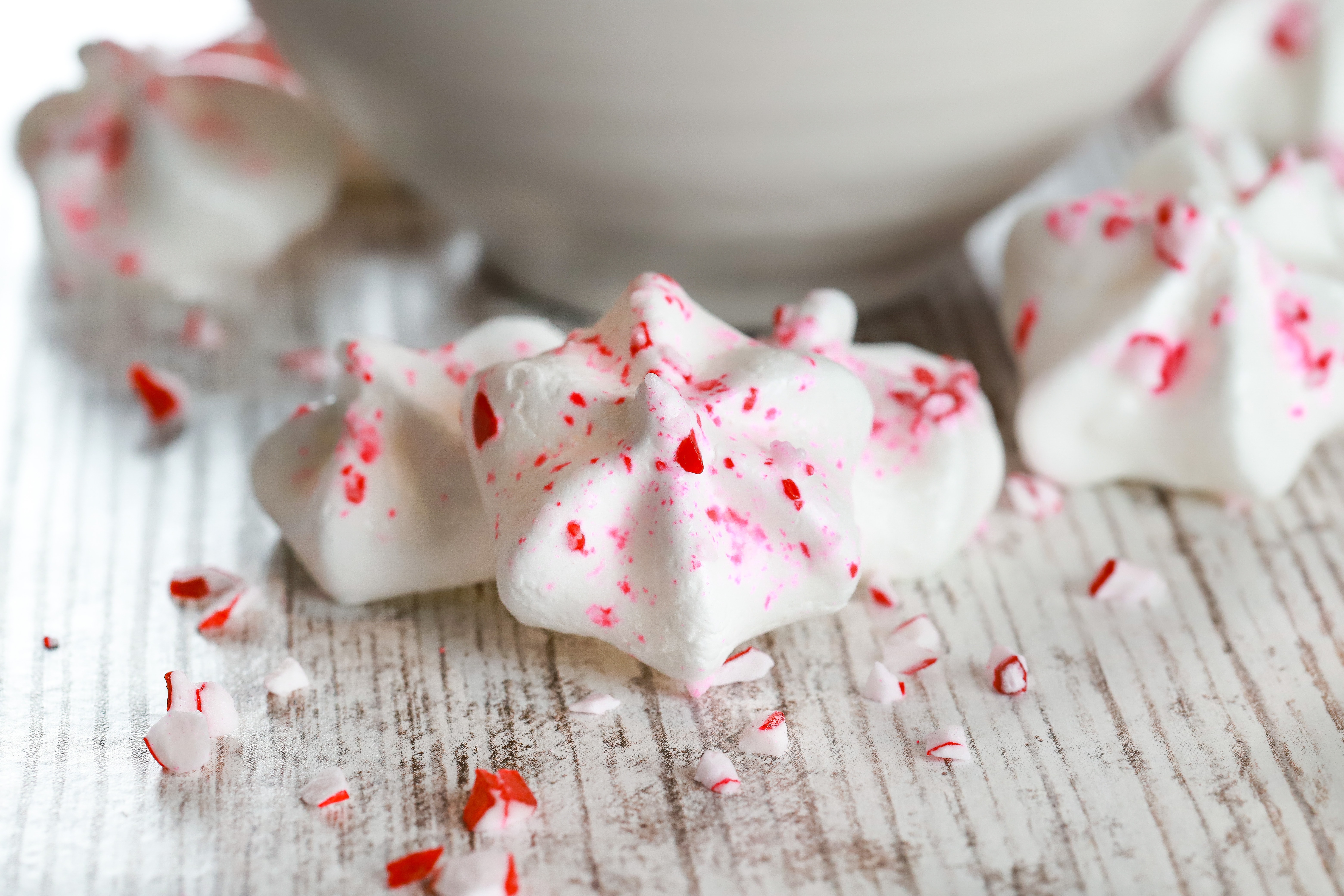 Up close image of Mini Peppermint Meringue Kisses in front of a white bowl. Recipe from A Kitchen Addiction