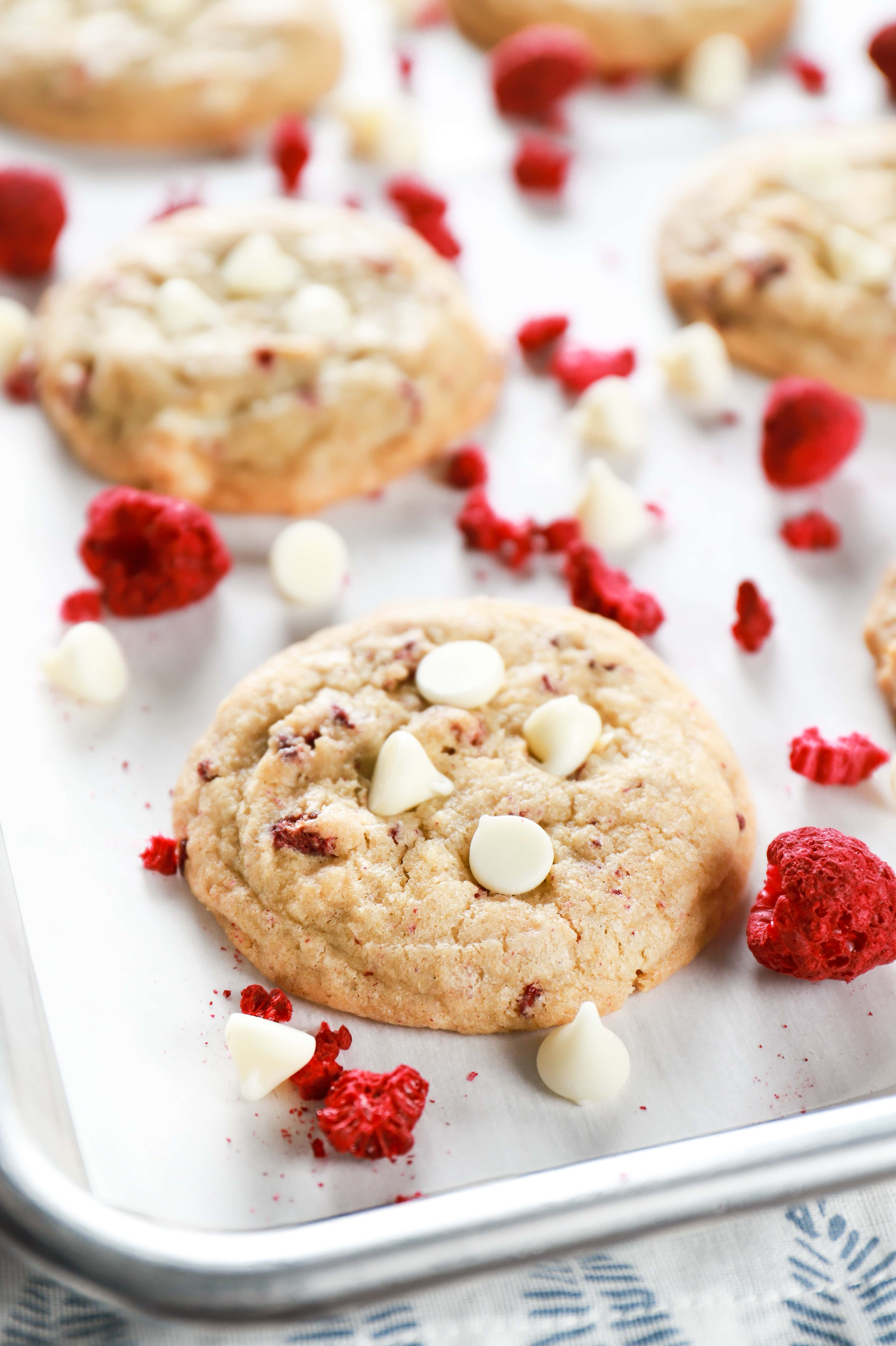 Up close image of a chewy white chocolate raspberry cookie on a parchment paper lined baking sheet. Recipe for cookies from A Kitchen Addiction