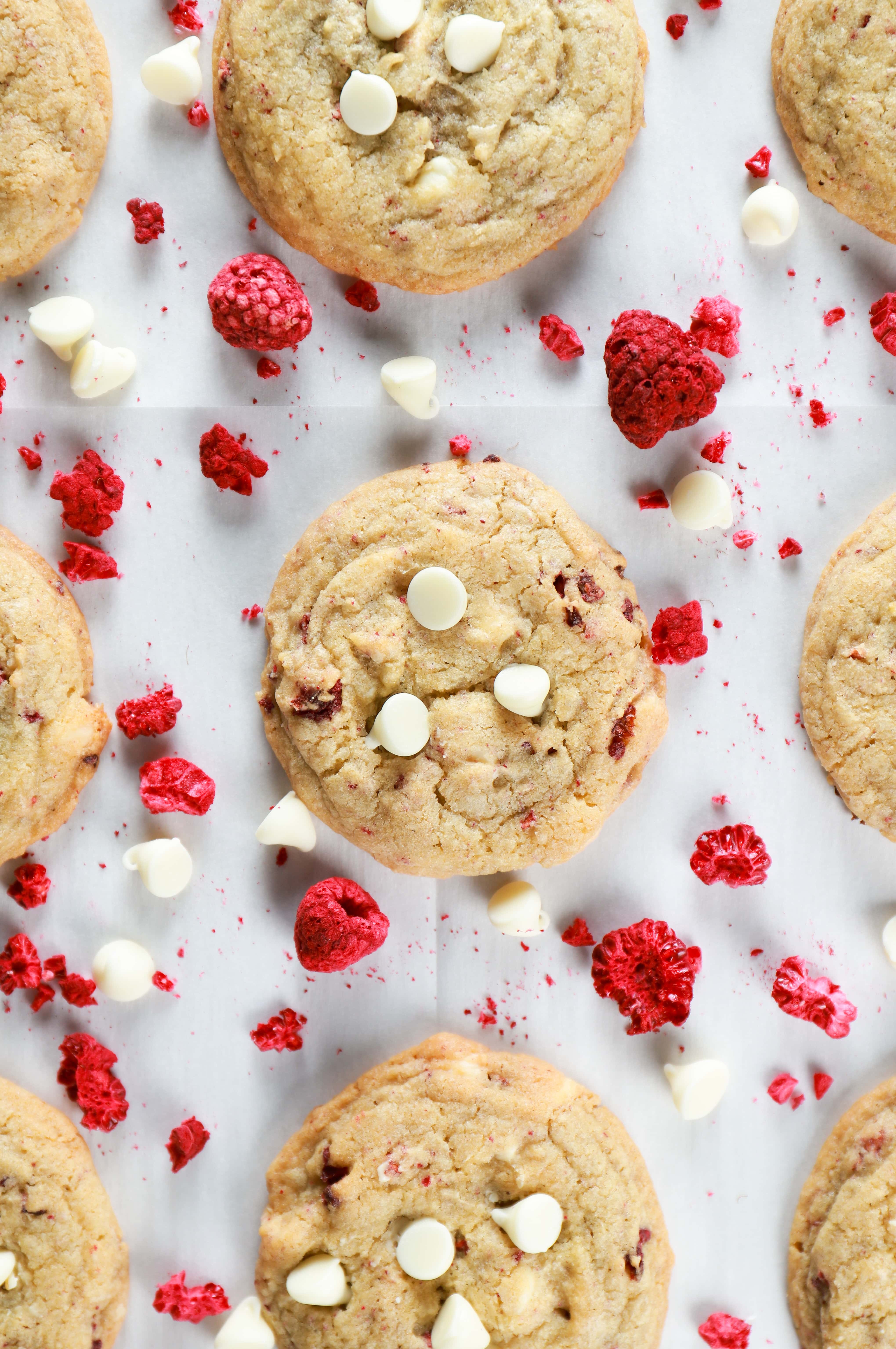 Overhead view of white chocolate raspberry cookies on a parchment paper lined cookie sheet. Recipe for cookies from A Kitchen Addiction