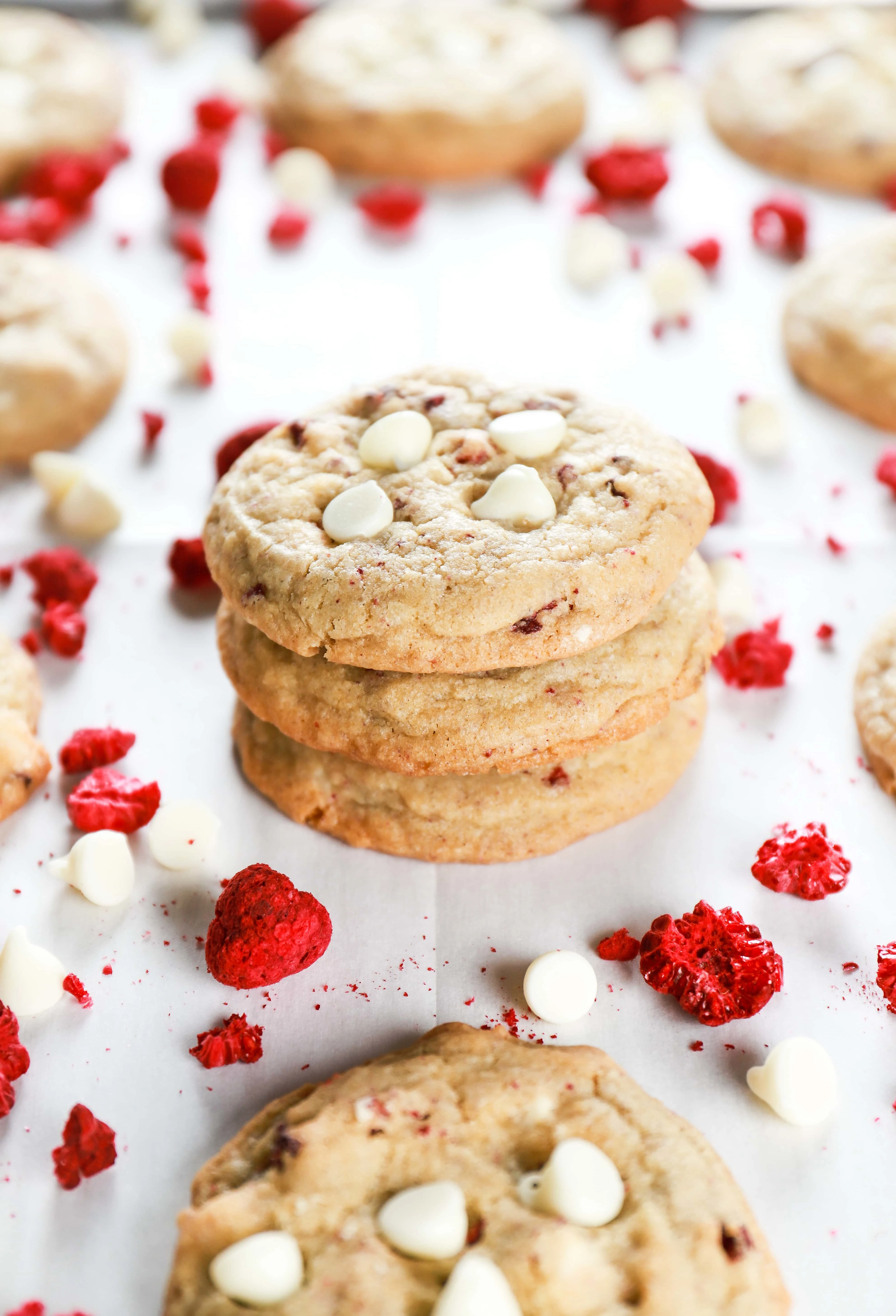 Stack of white chocolate raspberry cookies on a parchment paper lined cookie sheet. Recipe from A Kitchen Addiction