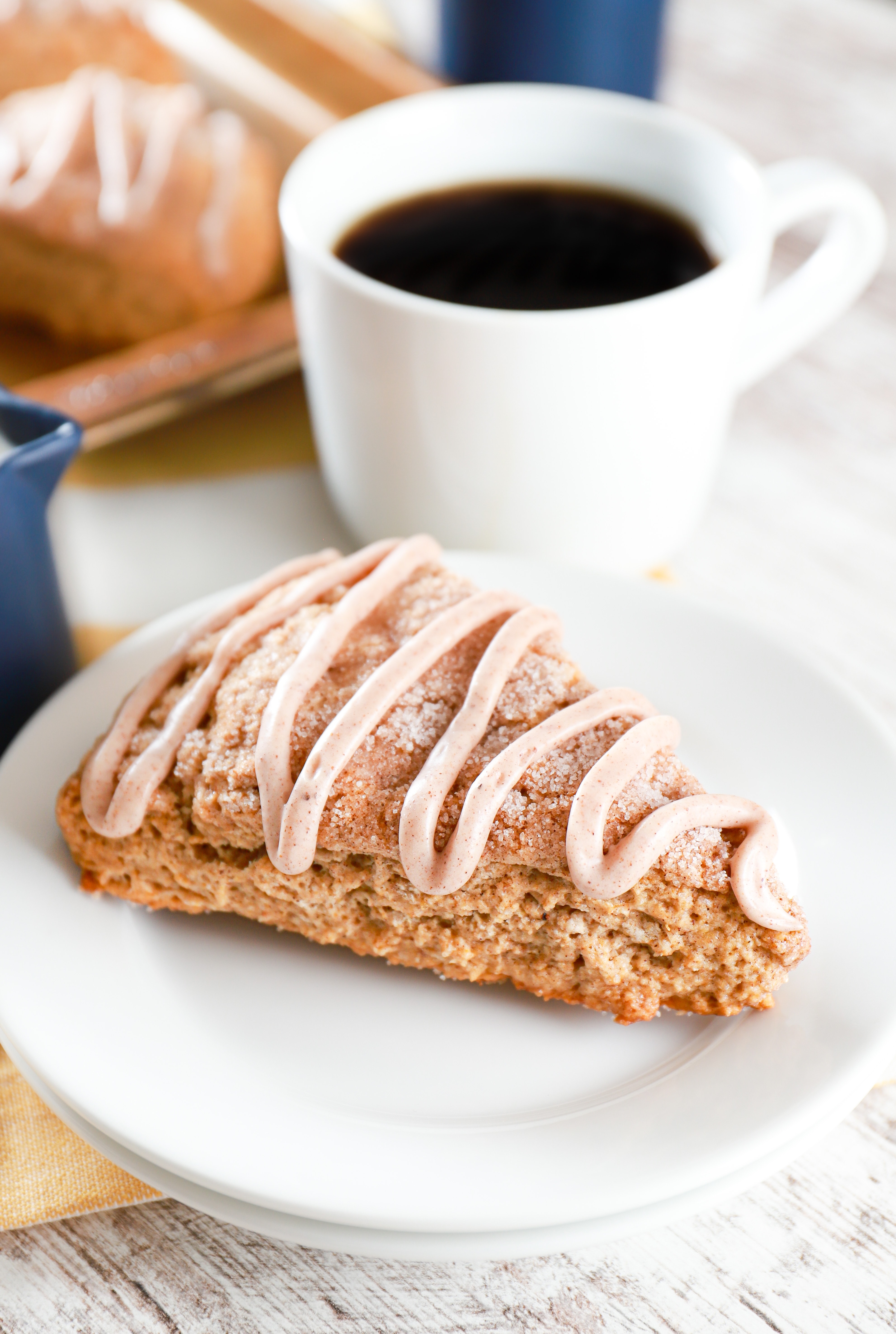 Banana Snickerdoodle Scone on a small with plate with coffee in the background. Recipe from A Kitchen Addiction