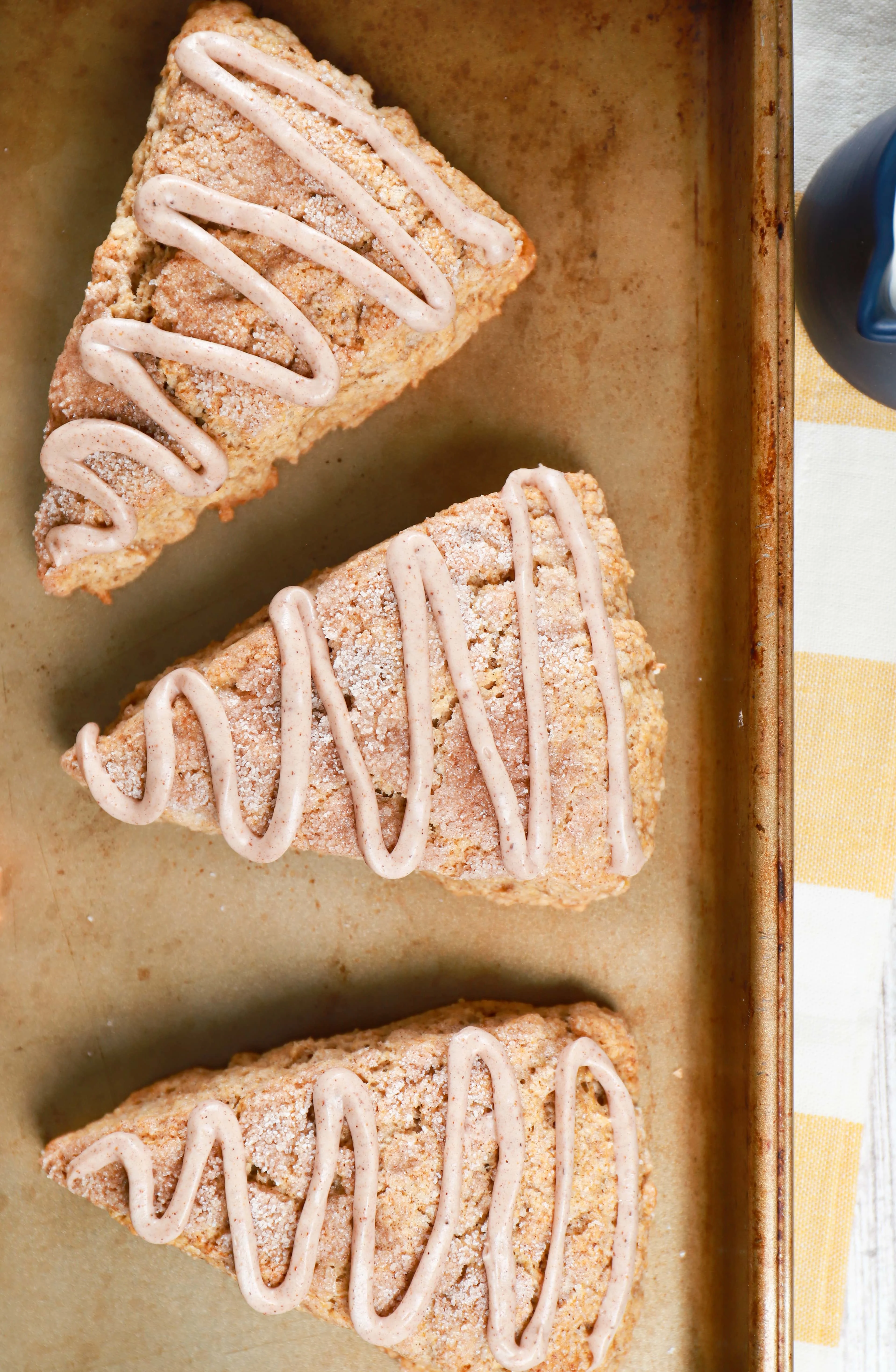 Overhead view of 3 snickerdoodle banana scones on a baking sheet. Recipe for scones from A Kitchen Addiction