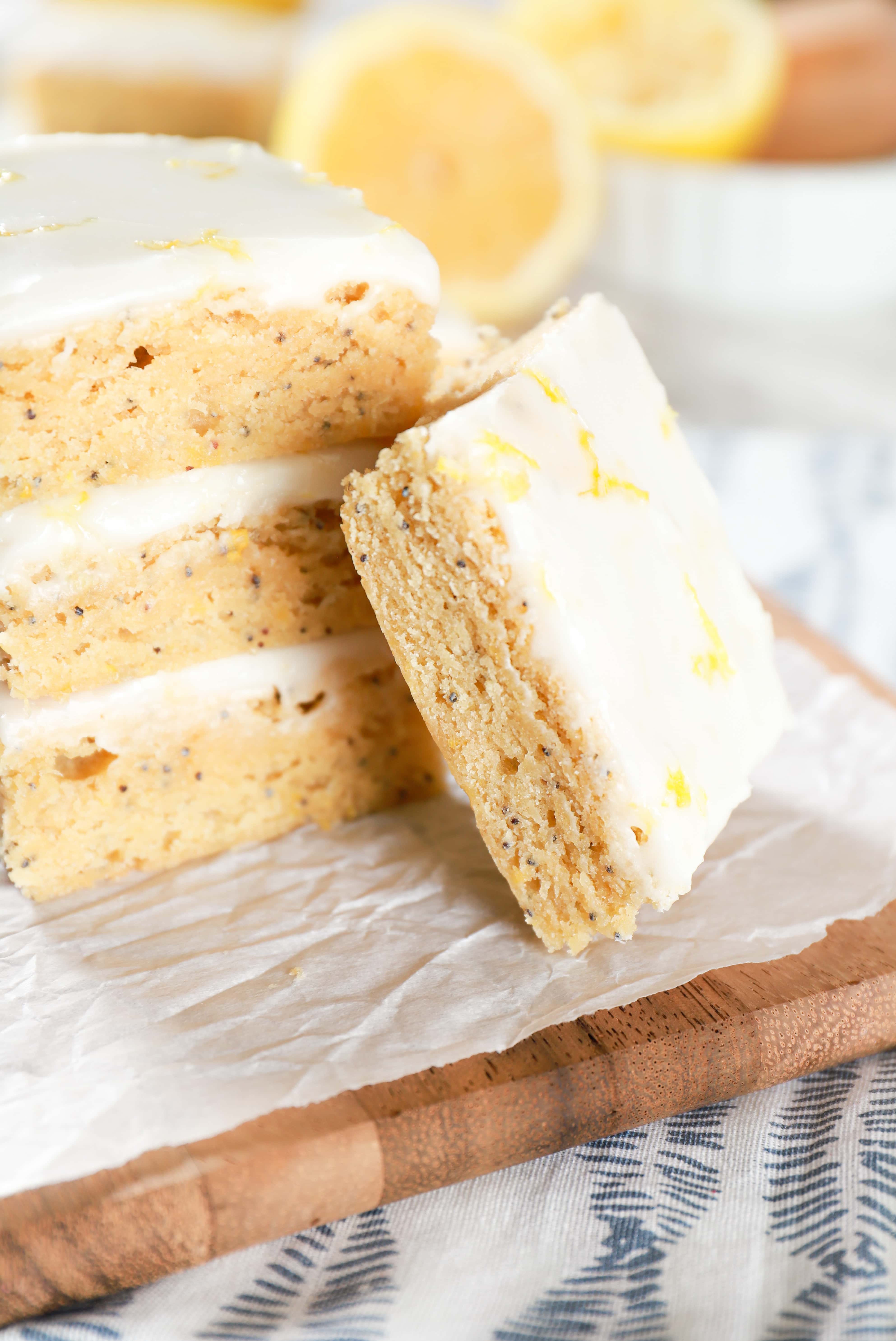 Stack of lemon poppy seed bars on a cutting board with one bar leaning against the stack. Recipe from A Kitchen Addiction